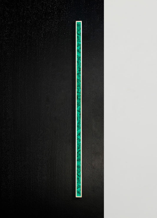A vertical strip of layered malachite with shades of green and swirling patterns, set within a thin metallic frame on a textured black background. The design has a contemporary and minimalist style with a focus on natural stone motifs.
