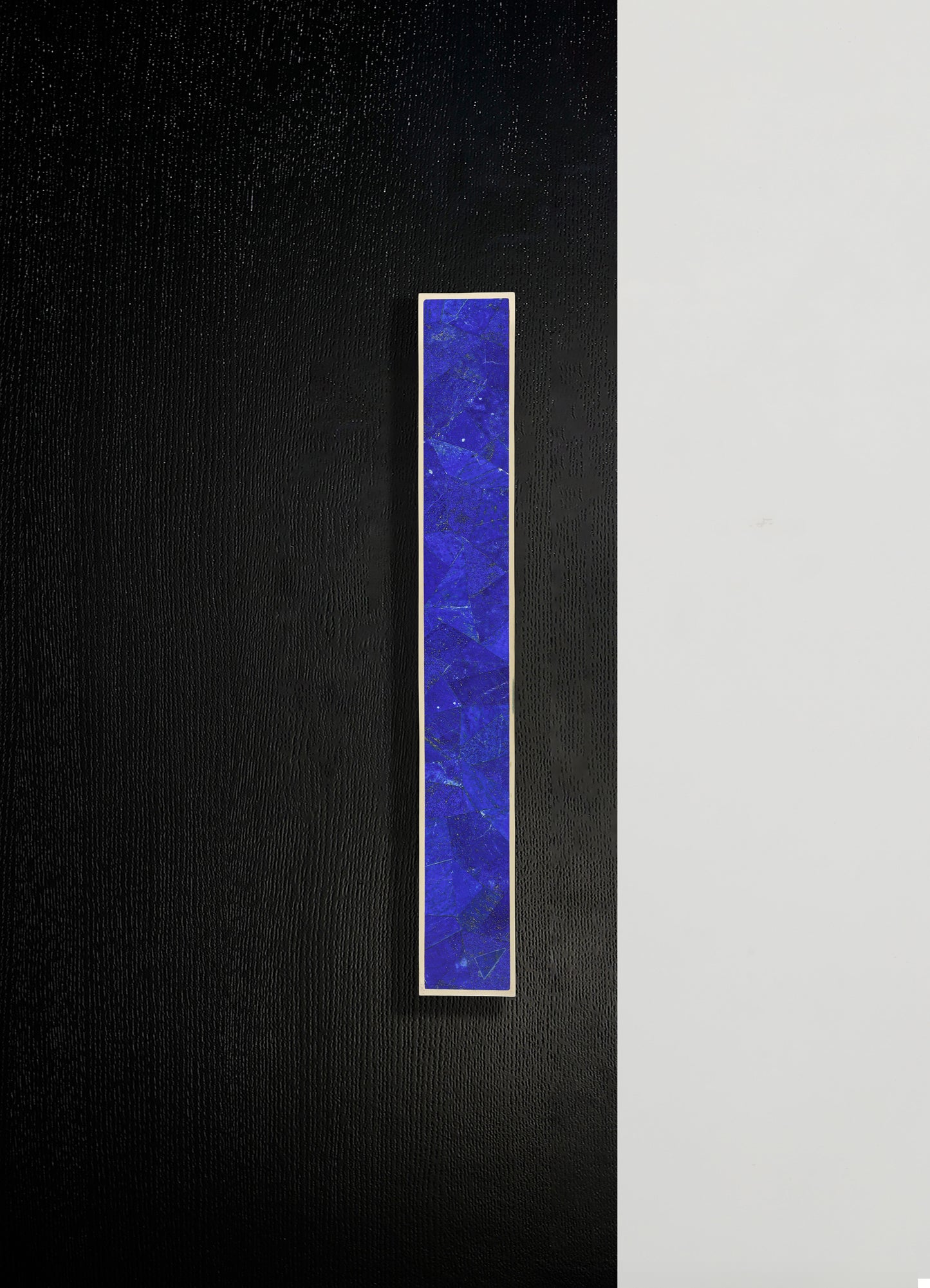 A rectangular wall-mounted art piece featuring a vibrant blue, textured pattern framed in white, set against a background split between black and white sections. The piece has a modern, abstract style with bold color contrast.