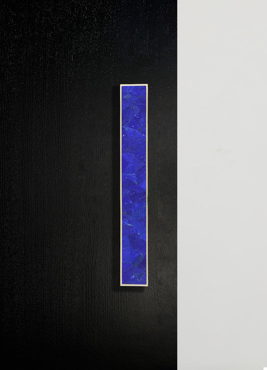 A rectangular wall-mounted art piece featuring a vibrant blue, textured pattern framed in white, set against a background split between black and white sections. The piece has a modern, abstract style with bold color contrast.