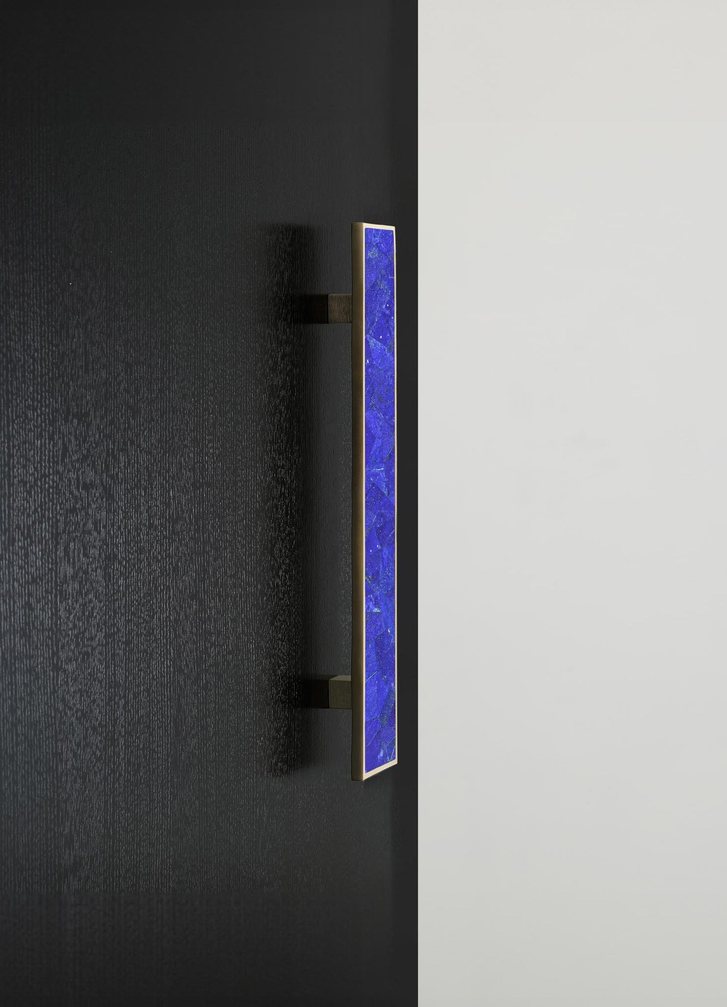 A wall-mounted light fixture with a rectangular blue stone or ceramic inlay framed in metal, set on contrasting black and white walls. The design features a sleek, contemporary style with a minimalist aesthetic.
