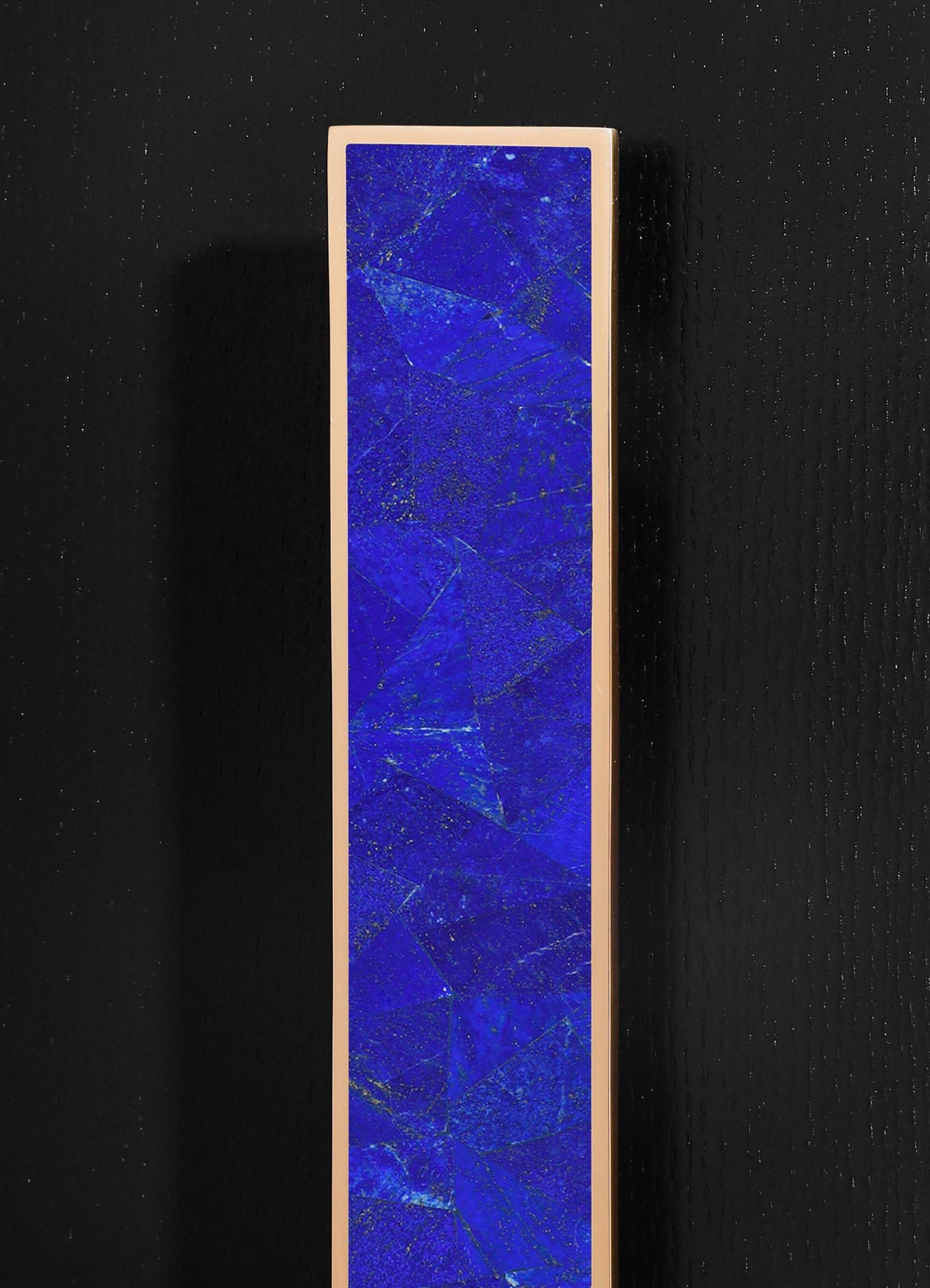 A tall, rectangular art piece with a deep blue, textured surface featuring gold veining and geometric patterns, framed in a light-colored border, set against a black background.