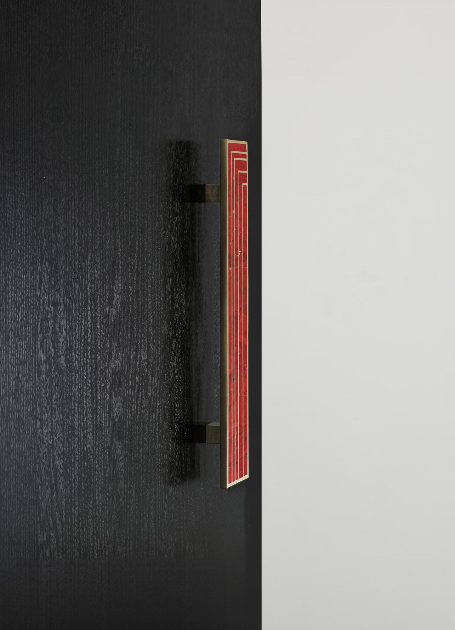A wall-mounted light fixture with a rectangular shape and a red geometric pattern, featuring a metallic gold border. The fixture is mounted on a black wall, contrasting with a white background.