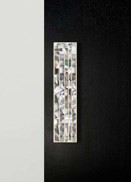 Decorative wall panel with mosaic shell inlay and a geometric metal frame, featuring an iridescent, multicolored pattern on a black and white background.