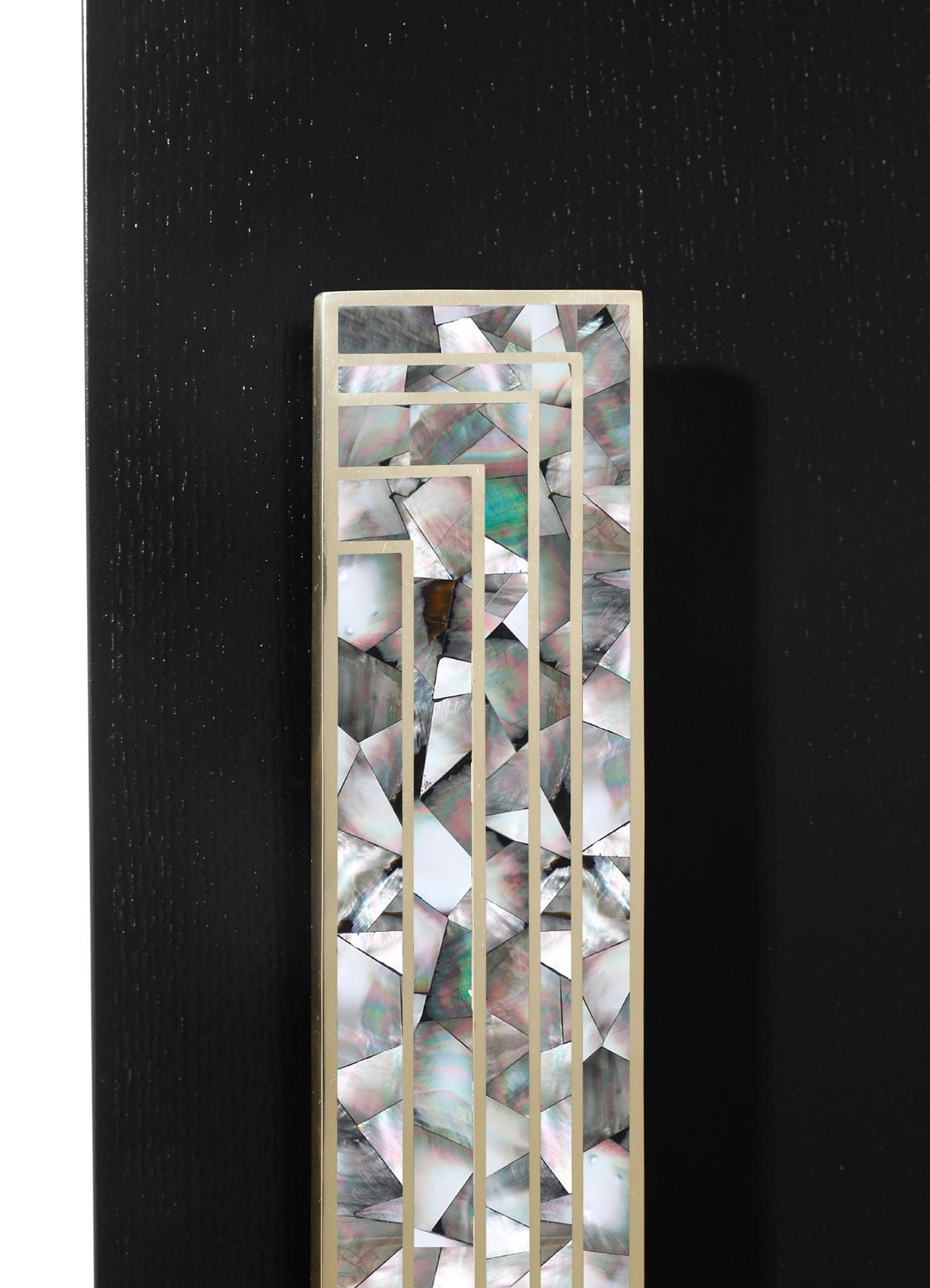 A decorative panel featuring irregularly shaped mother-of-pearl inlays arranged in a geometric pattern, framed with a light-colored border. The design emphasizes iridescent, natural shell tones against a dark background.