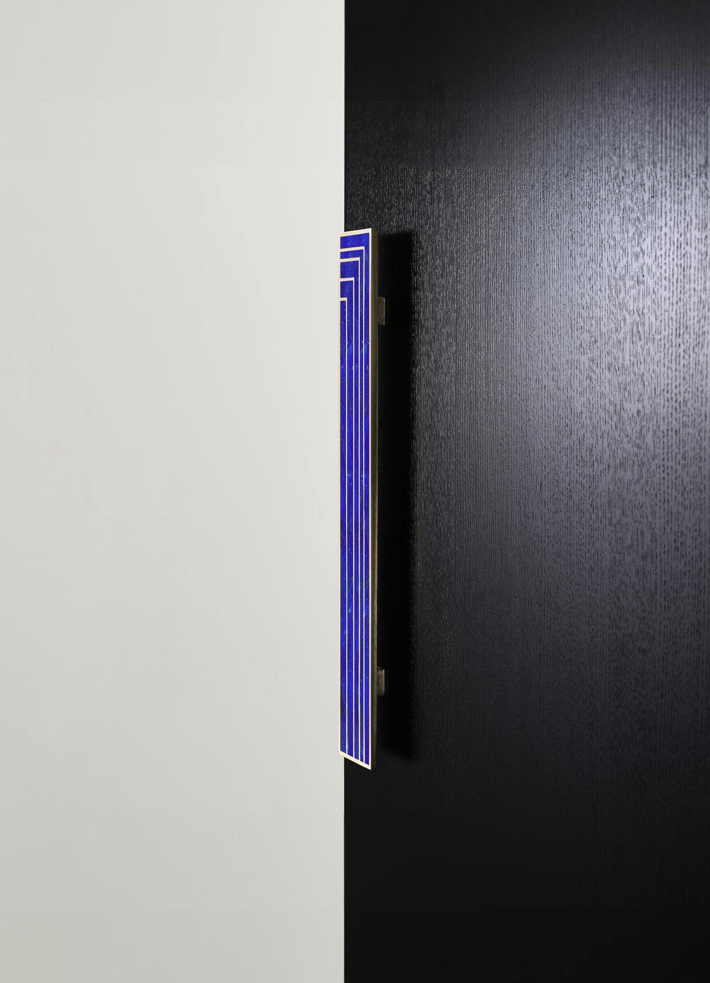 A modern decorative LED wall light with a narrow, rectangular shape featuring blue and white geometric lines, mounted on a wall divided into black and white sections.