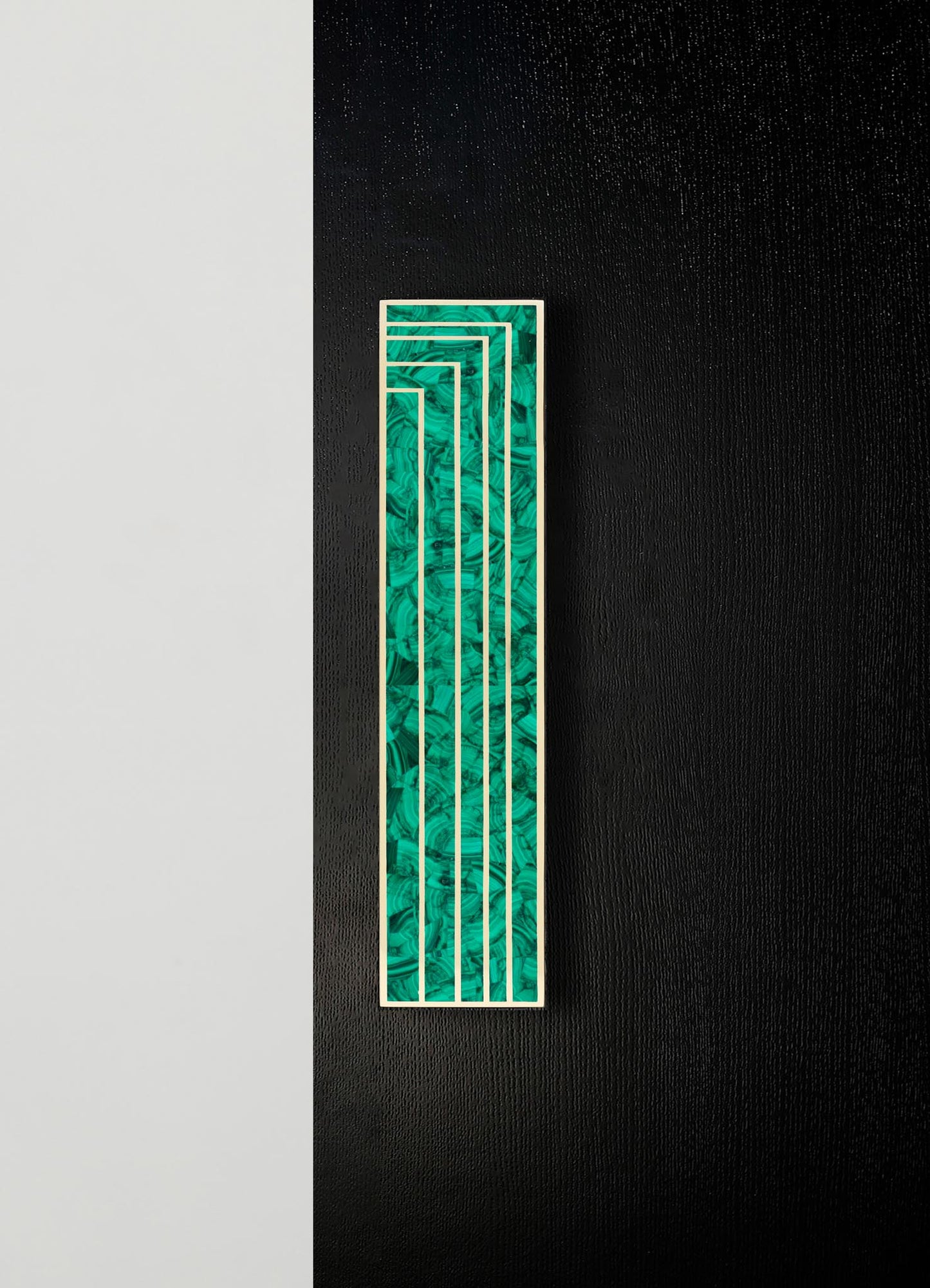 A decorative wall panel with a rectangular shape, featuring a green marbled pattern and a gold metal frame, mounted on a black textured wall.