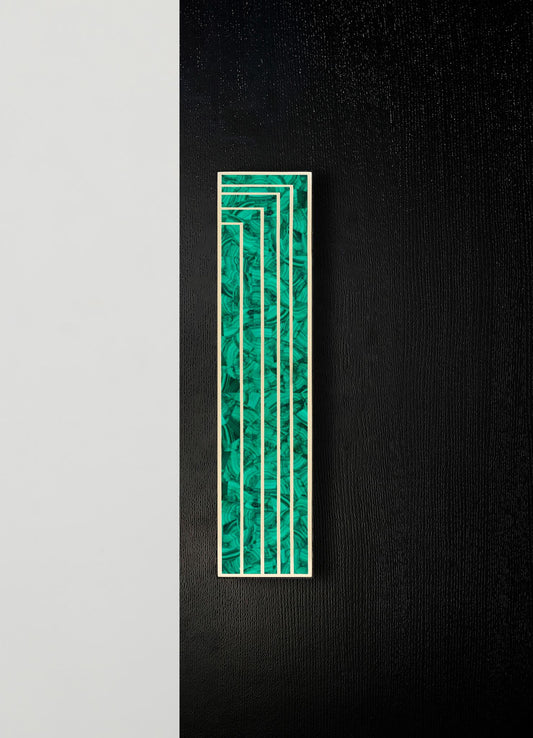 A decorative wall panel with a rectangular shape, featuring a green marbled pattern and a gold metal frame, mounted on a black textured wall.
