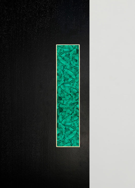 A tall, rectangular decorative art piece with a green malachite-inspired pattern framed in light wood, mounted on a wall with a bold black and neutral gray color contrast.