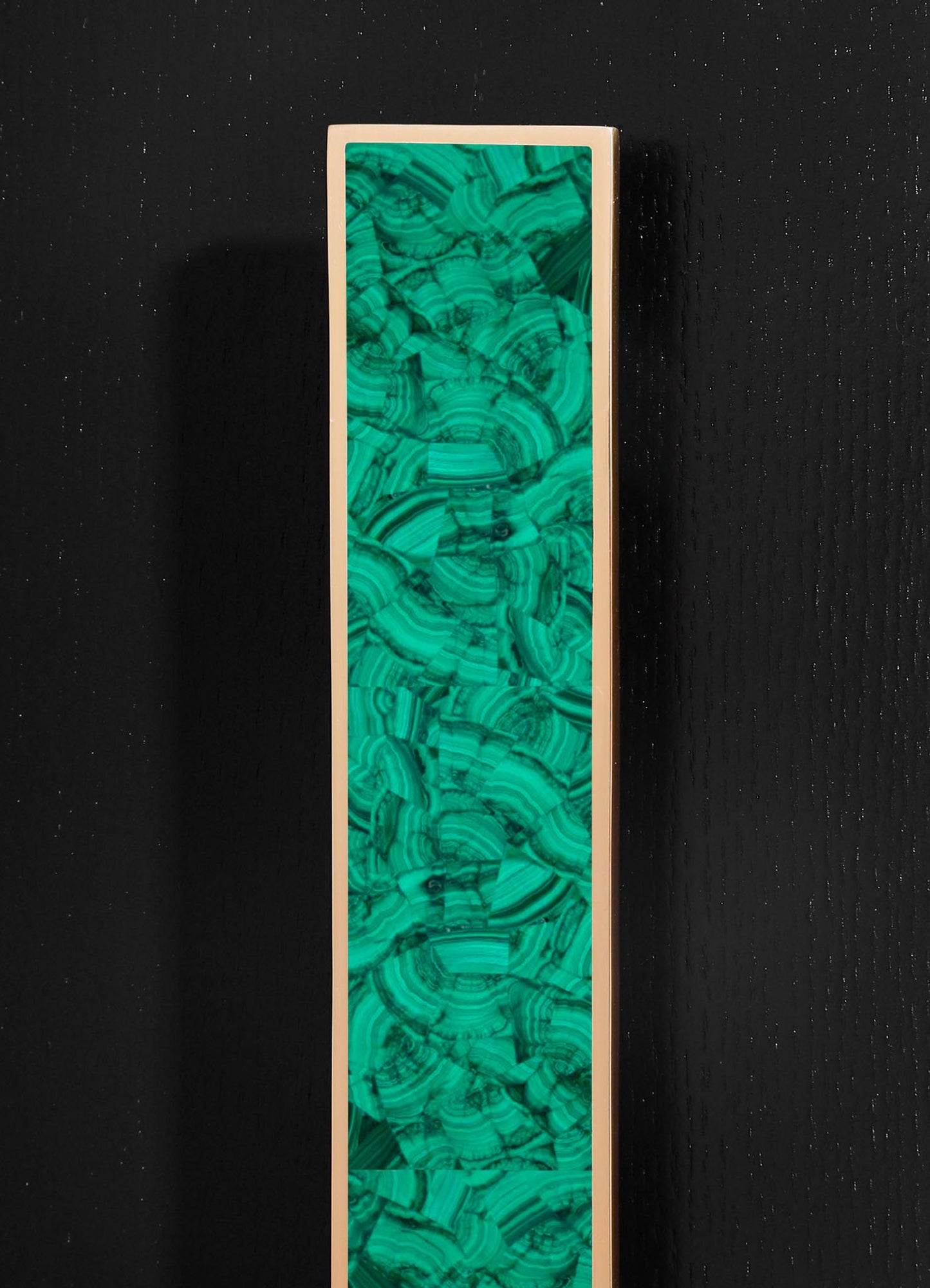 A tall, rectangular decorative panel featuring a vibrant green malachite pattern with swirling natural veining, framed in a gold or brass border, set against a black textured background.