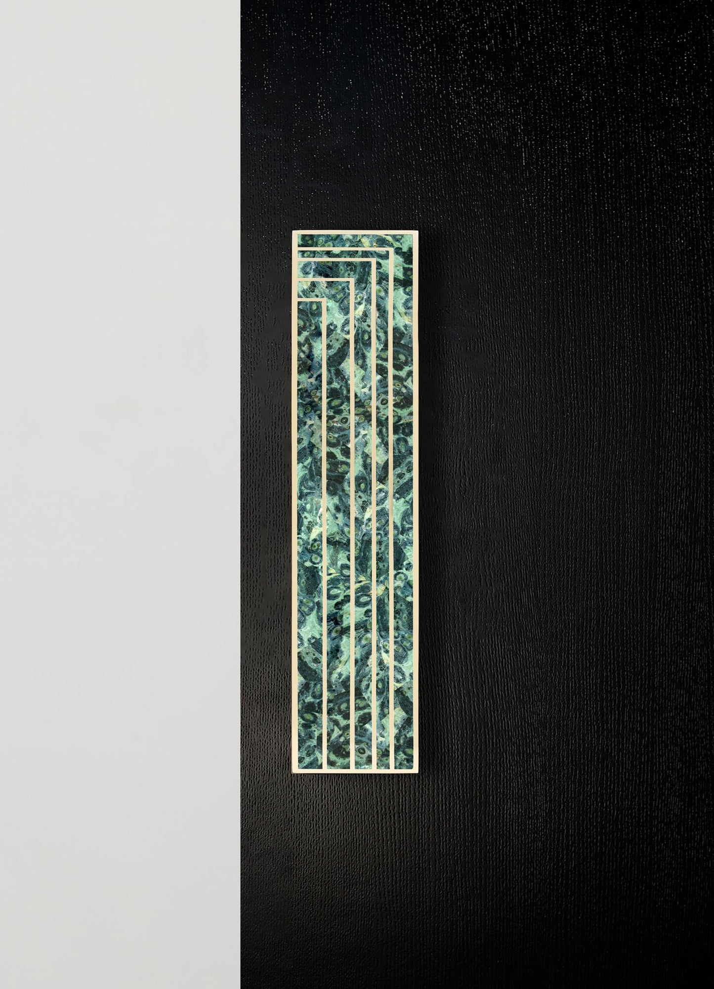 A decorative wall panel with a rectangular shape and a pattern resembling swirling blue and green marbled textures, framed by a thin metallic border, mounted on a black textured wall.