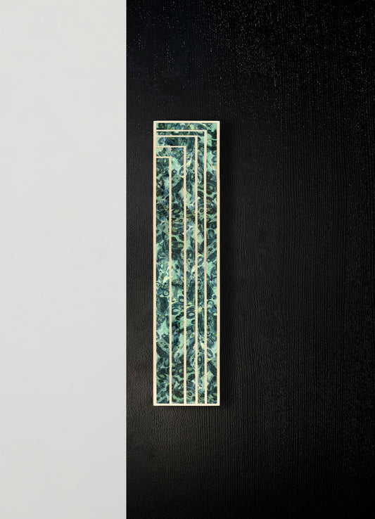 A decorative wall panel with a rectangular shape and a pattern resembling swirling blue and green marbled textures, framed by a thin metallic border, mounted on a black textured wall.