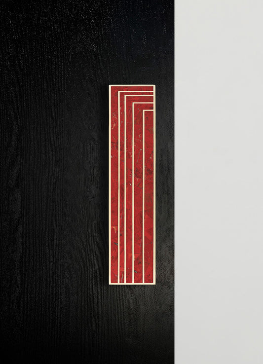A tall rectangular wall art piece with a red marble background and white geometric lines, mounted on a black textured wall adjacent to a smooth white surface.