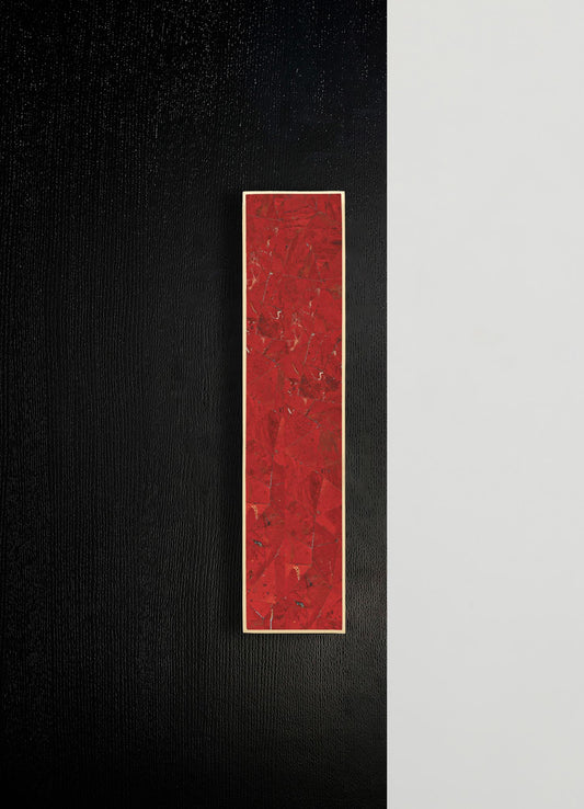A rectangular artwork with a red, textured surface featuring abstract, crack-like patterns, framed with a thin white border, mounted on a black and white wall.