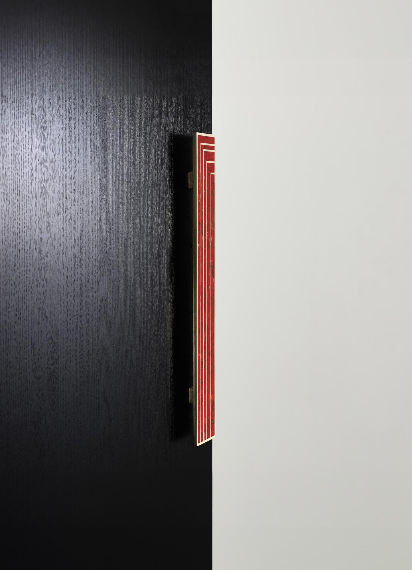 A vertical, rectangular decorative wall panel with a red and cream geometric pattern, mounted on a black textured wall. The panel has a contemporary style with bold lines and striking color contrast.