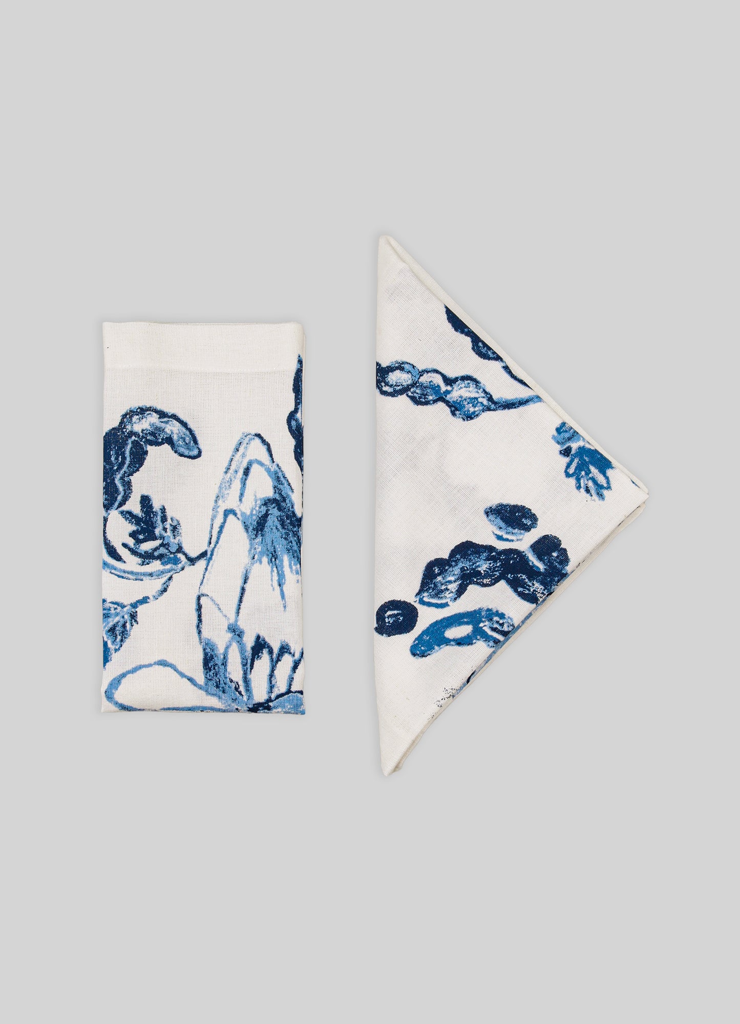 Two folded napkins with blue floral patterns on a gray background
