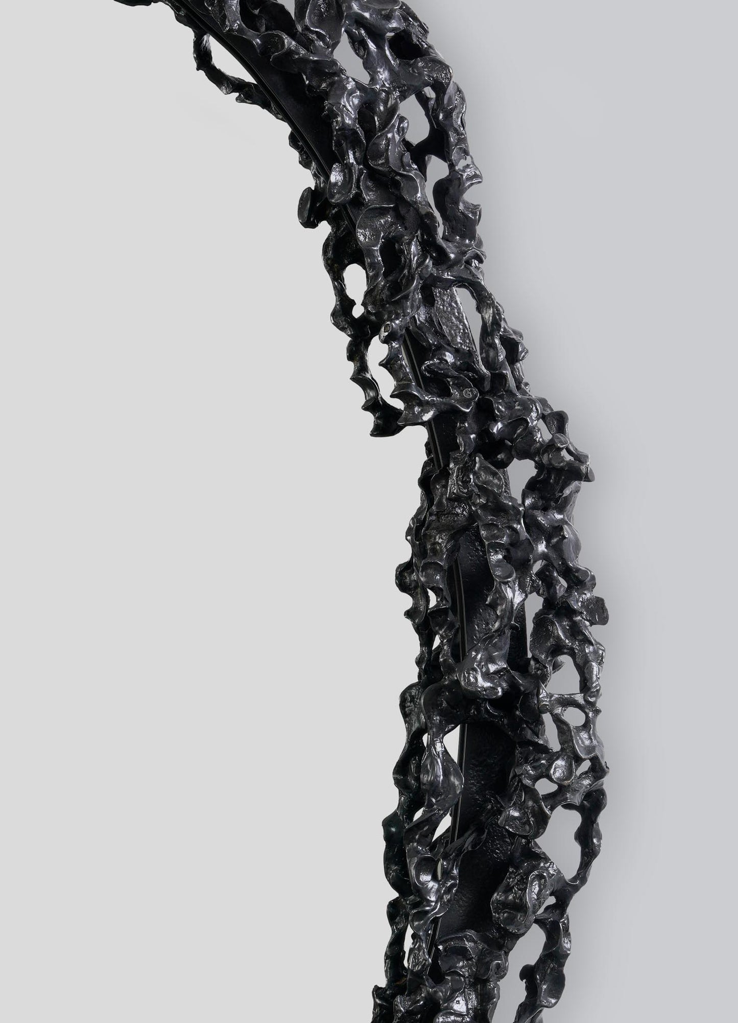 A close-up of the Andaman Mirror Large by VIYA, featuring a sculptural, textured black frame with irregular, cave-inspired forms, set against a plain light gray background.