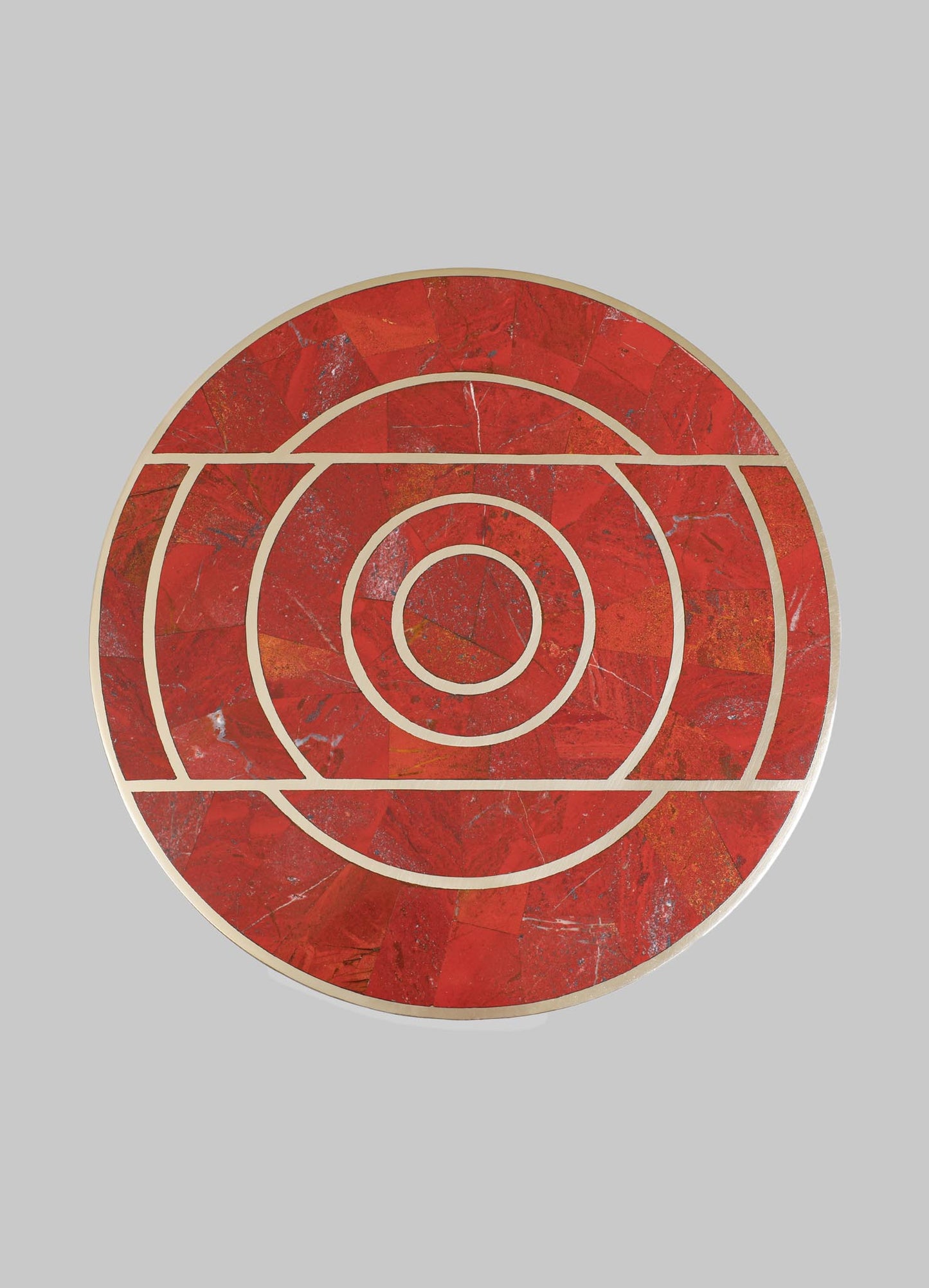 A round tray with a geometric pattern featuring concentric circles and straight lines, crafted from red and orange marble with gold-tone metal edging.