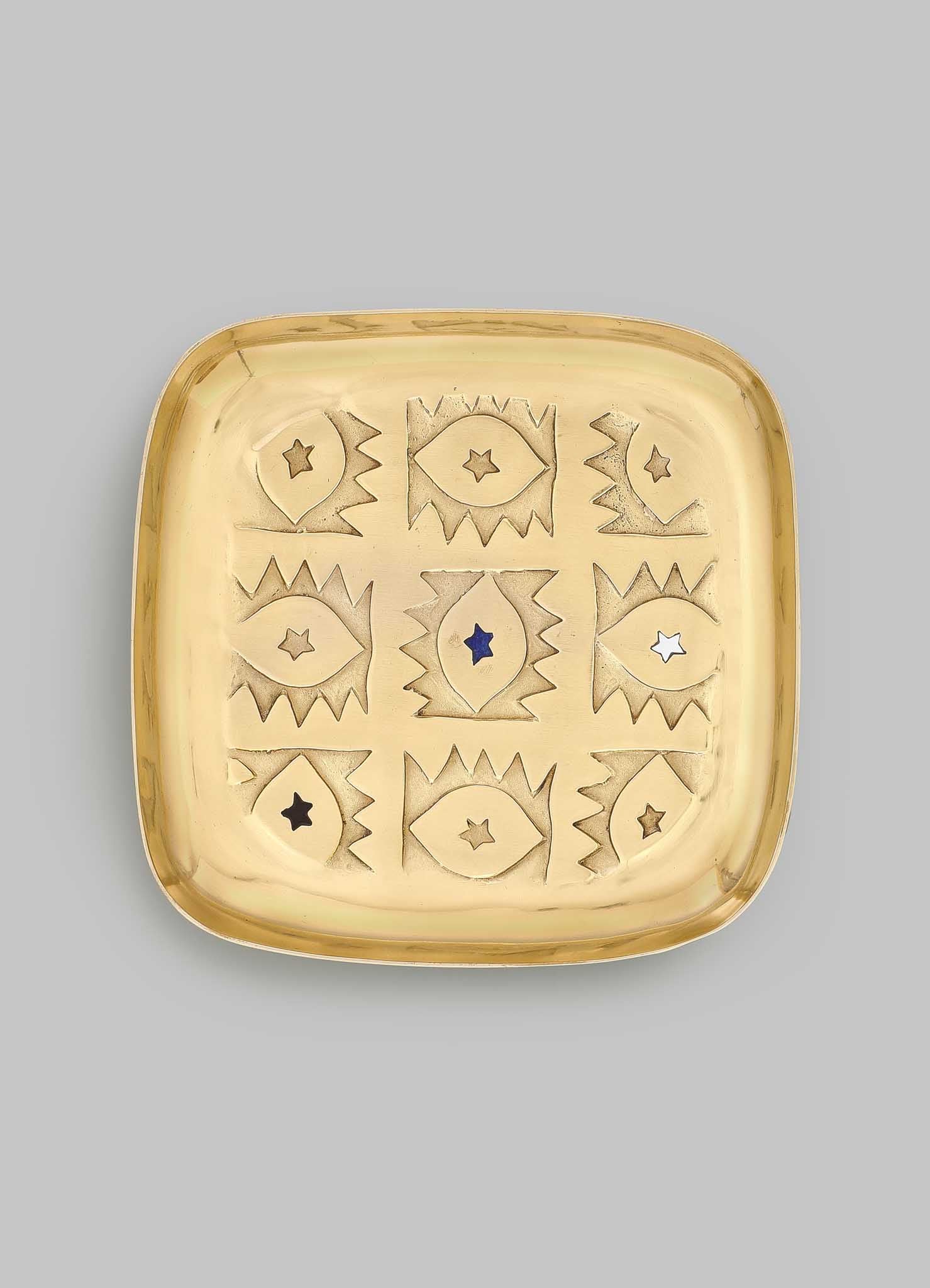 The VIYA Evil Eye Trinket Tray Large is a square brass tray with rounded corners, engraved with nine abstract evil eyes—each with a star center—in a 3x3 grid, symbolizing protection and elegance.