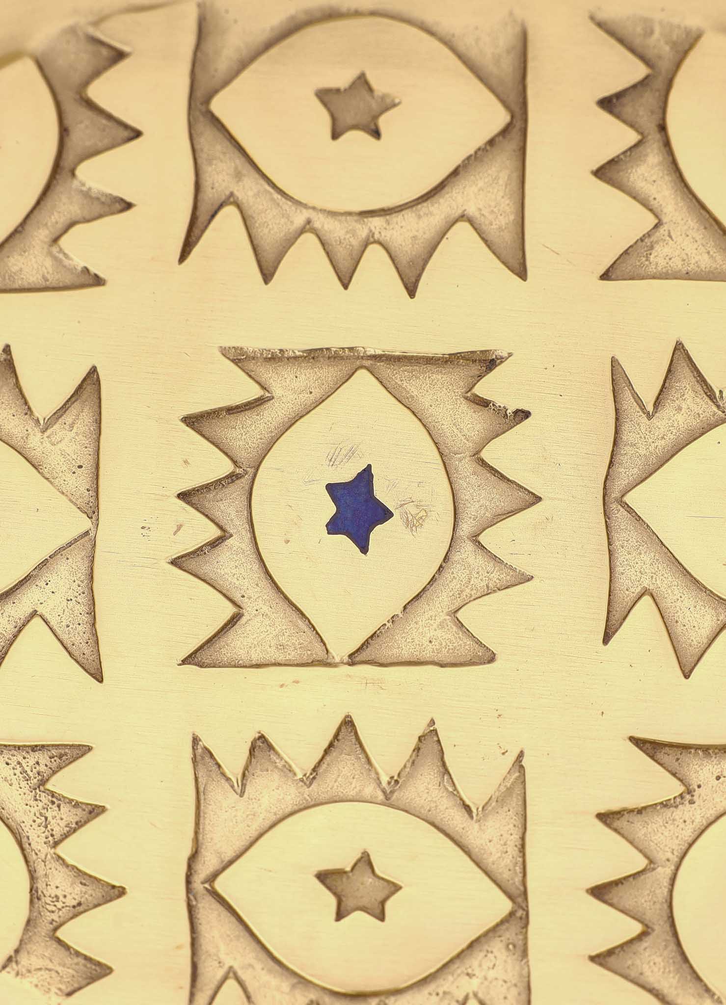 The VIYA Evil Eye Trinket Tray Large features a gold surface engraved with repeating eye motifs, each with a star center; one eye has a blue star like the classic evil eye, while others display brown stars.