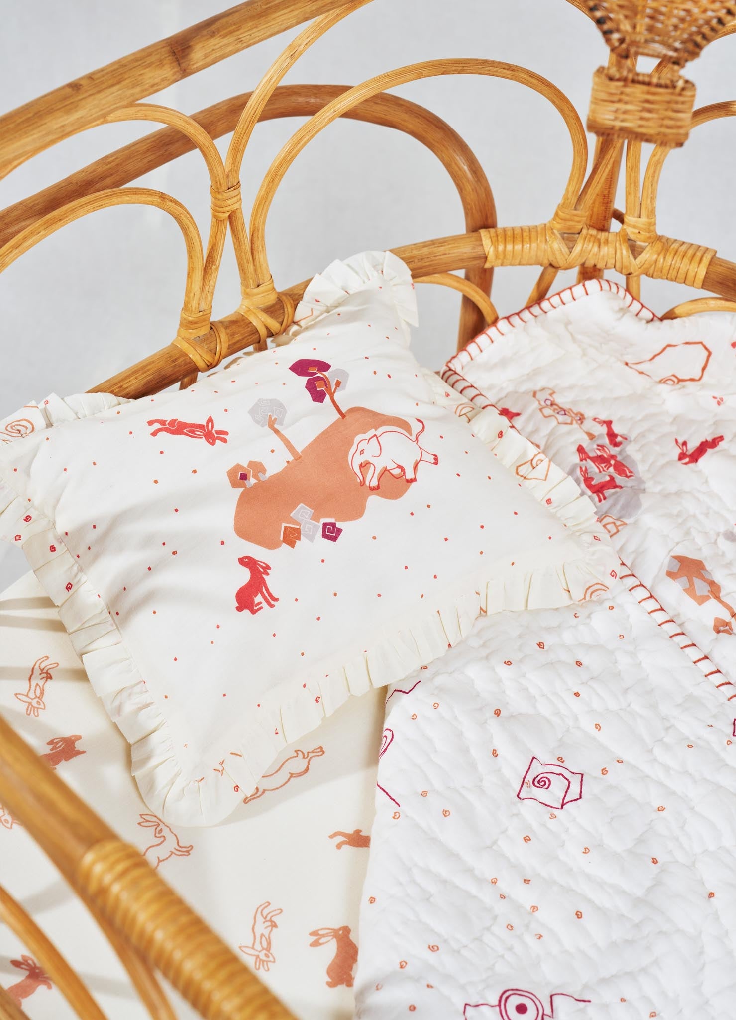 Children's bedding set featuring quilted and ruffled pillowcases with playful animal and abstract motifs in soft beige, brown, red, and pink tones. Made from quilted fabric with a lightweight, textured appearance, styled in a whimsical and cozy design.
