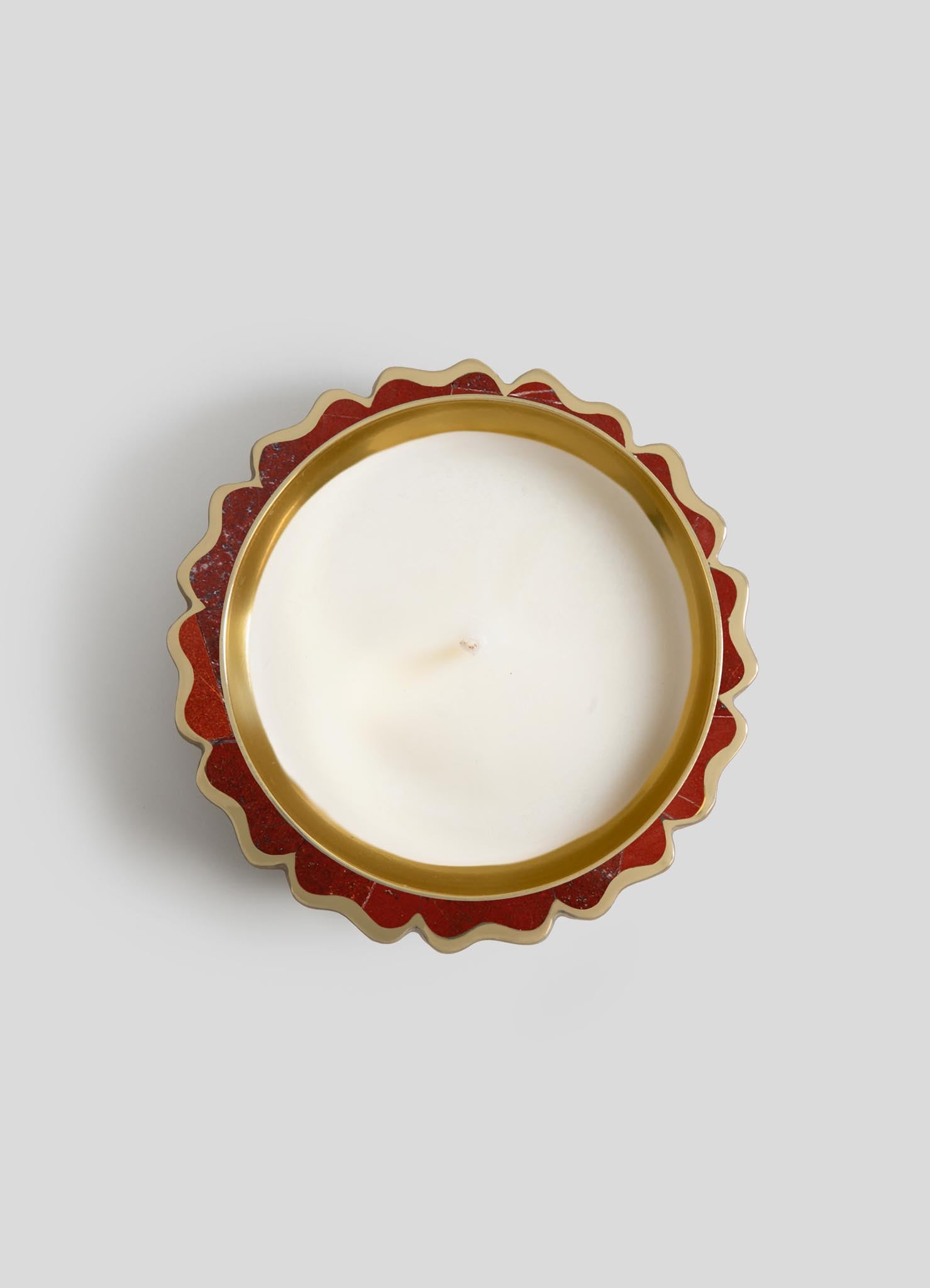 A top view of Viya's Mystical Marigold Red - Scented Candle Diya Large in a white round candle, set in a gold and red scalloped tin inspired by ancient metalworking, against a plain light gray background.