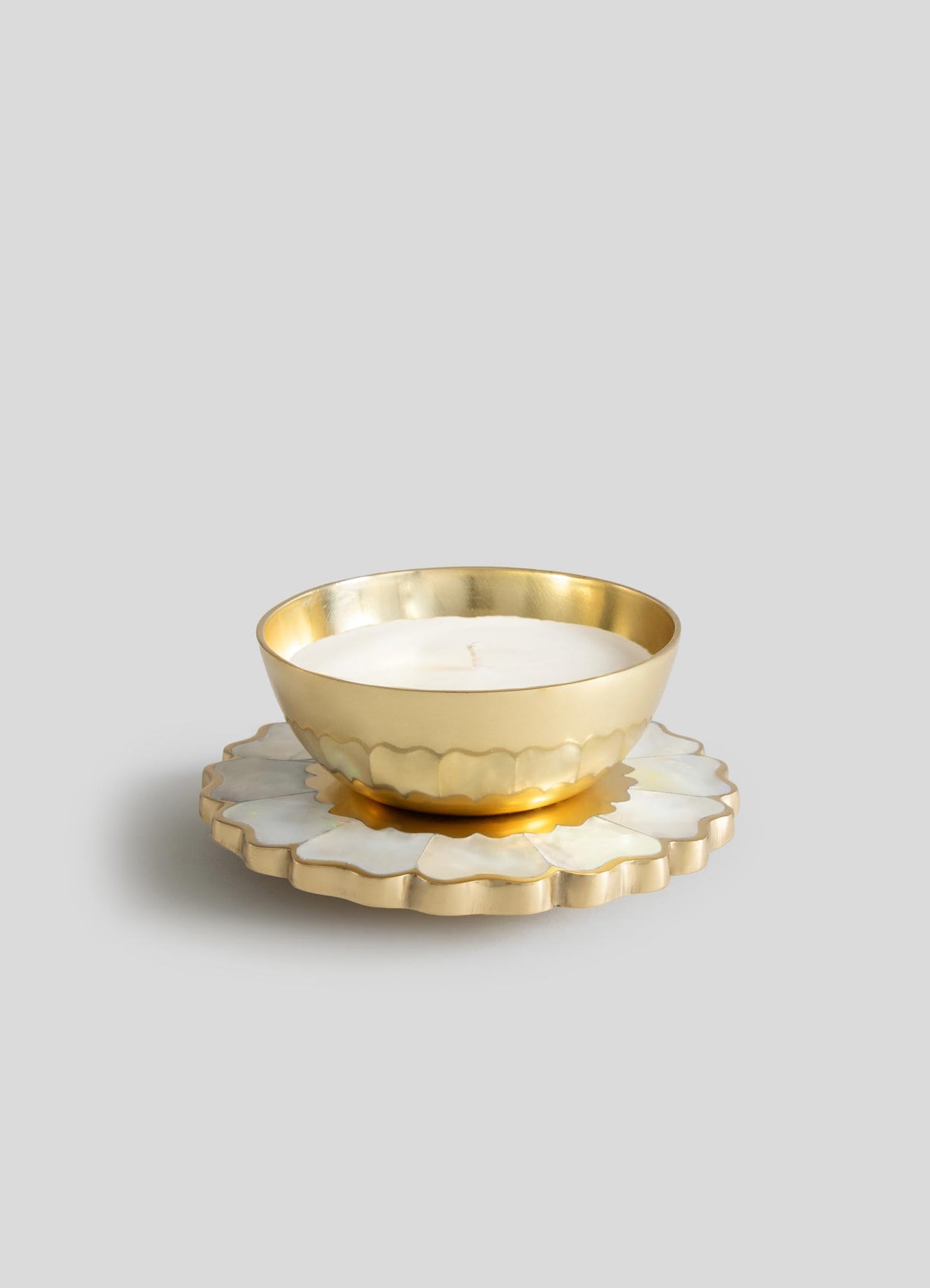 The Viya Mystical Marigold White Scented Candle Diya Large features a round gold metal holder with a white candle, set on a scalloped white and gold base—a modern heirloom that stands out against a plain grey background.