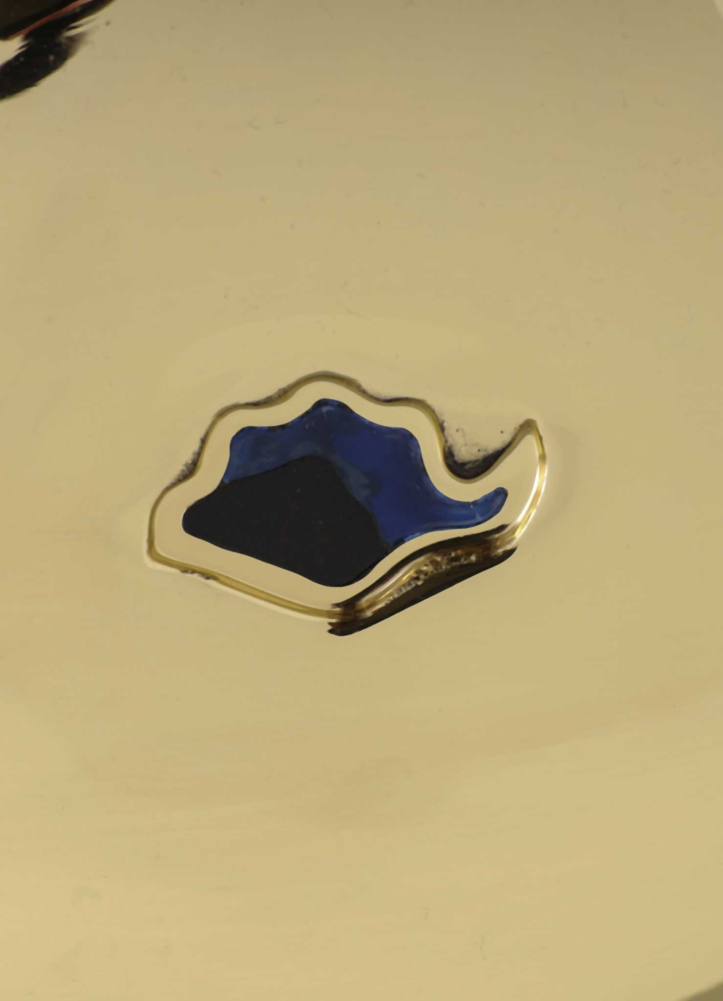 A close-up of VIYA's Nazar Battu Trinket Bowl Large, showcasing a shiny gold surface with an abstract wavy blue and gold inlay at the center, resembling a modern protective Nazar amulet.