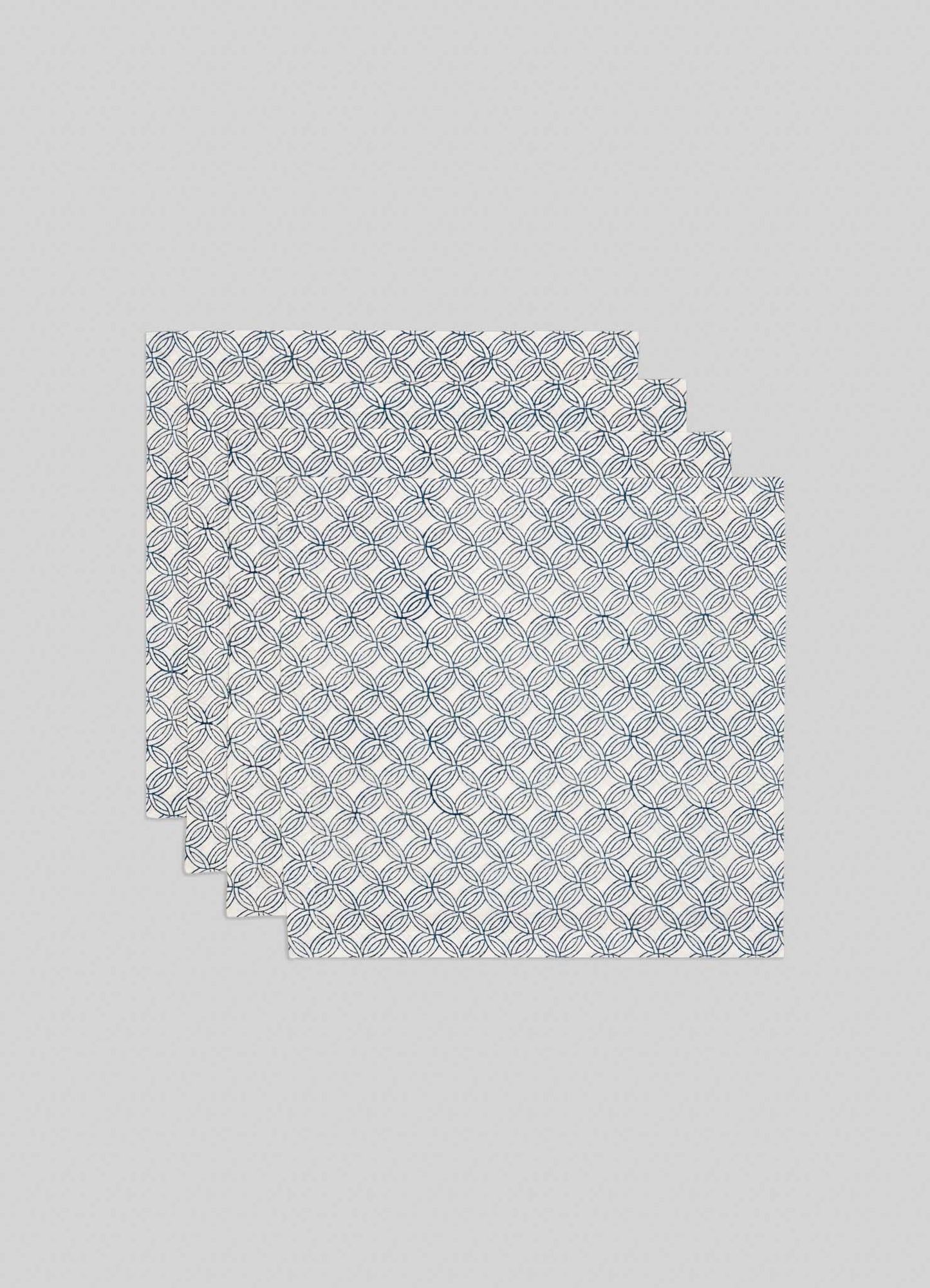 The Viya Paigah Navy Napkins - Set of 4 showcase a blue geometric circle pattern inspired by Hyderabad’s Indo-Islamic architecture, arranged in a slightly overlapping stack on a plain light gray background.