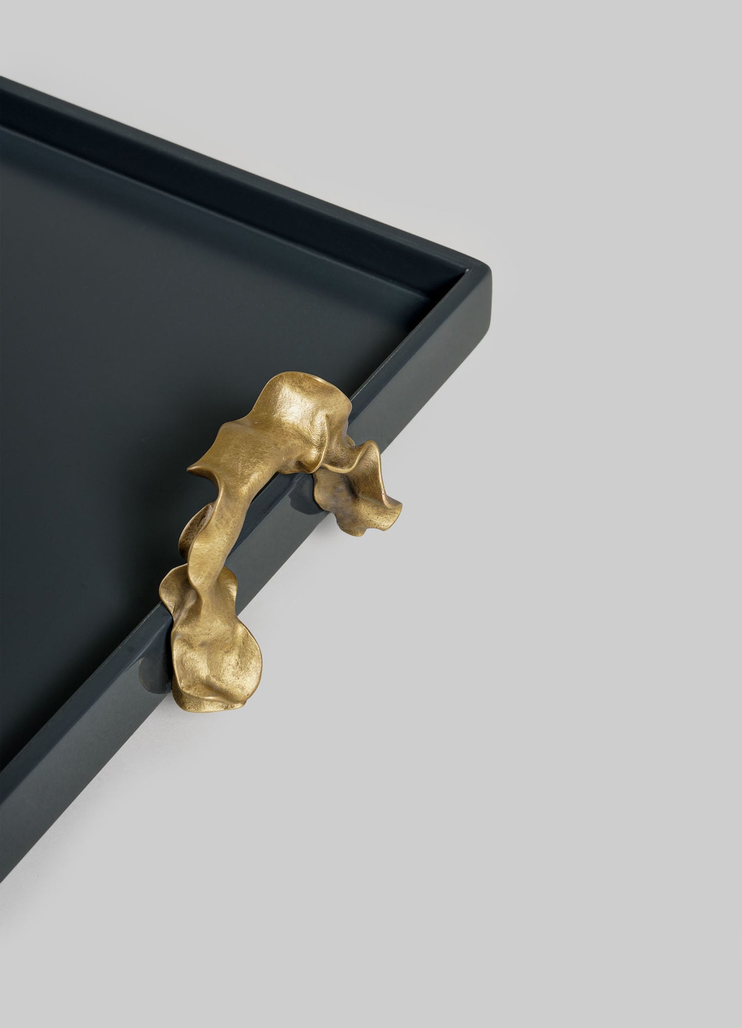 The VIYA Saffron Dark Blue Towel Tray features a matte black rectangular design with an abstract gold handle on one corner, displayed against a plain light gray background.