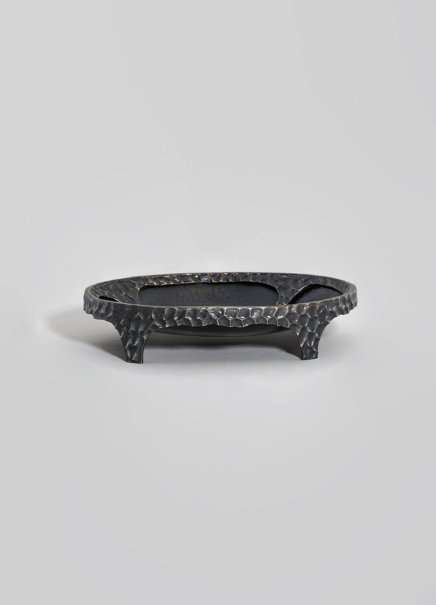 Black hammered metal tray with a textured surface and curved legs.