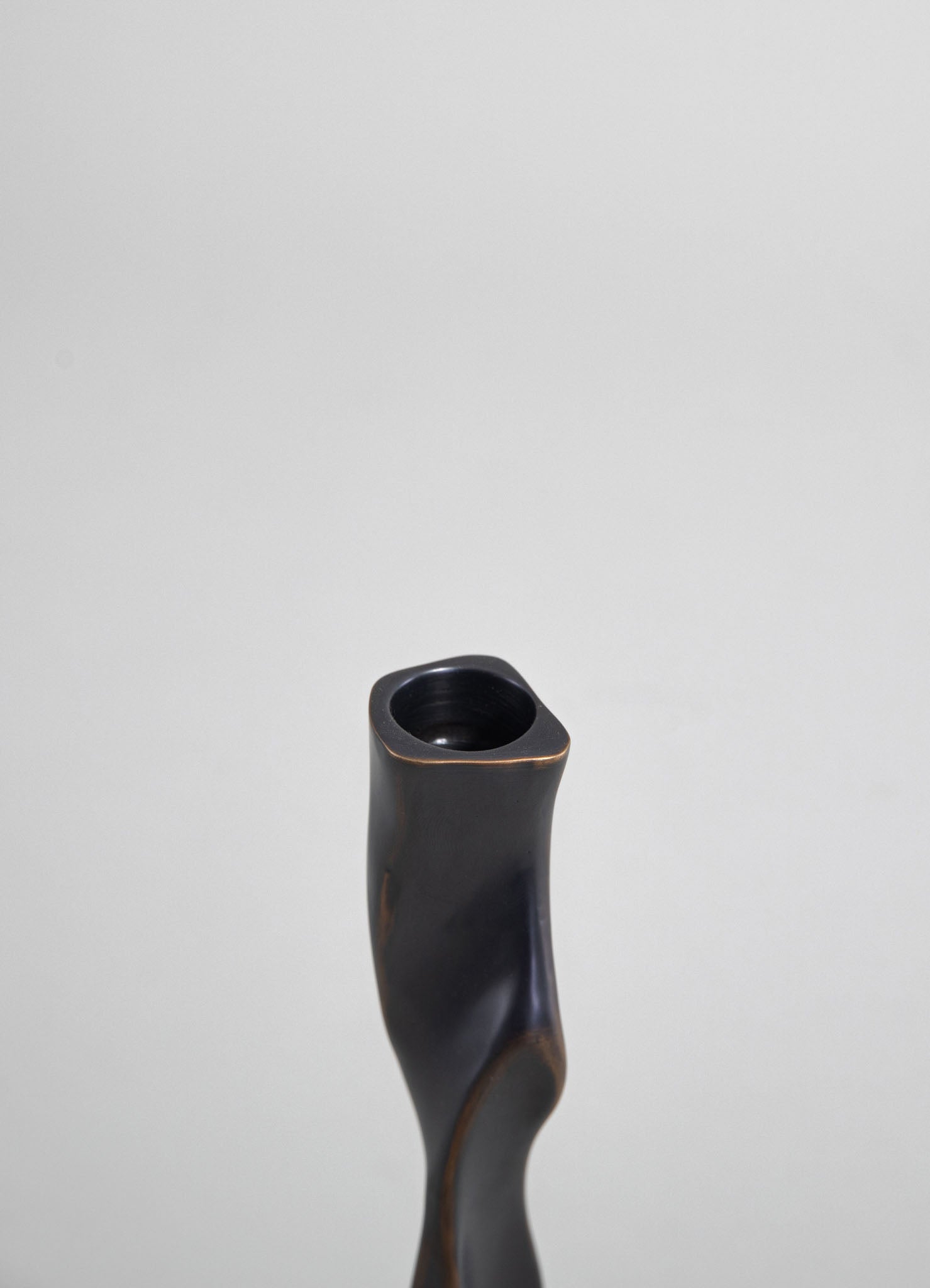A black ceramic vase with a matte finish, featuring an organic, curved shape and a narrow opening at the top.