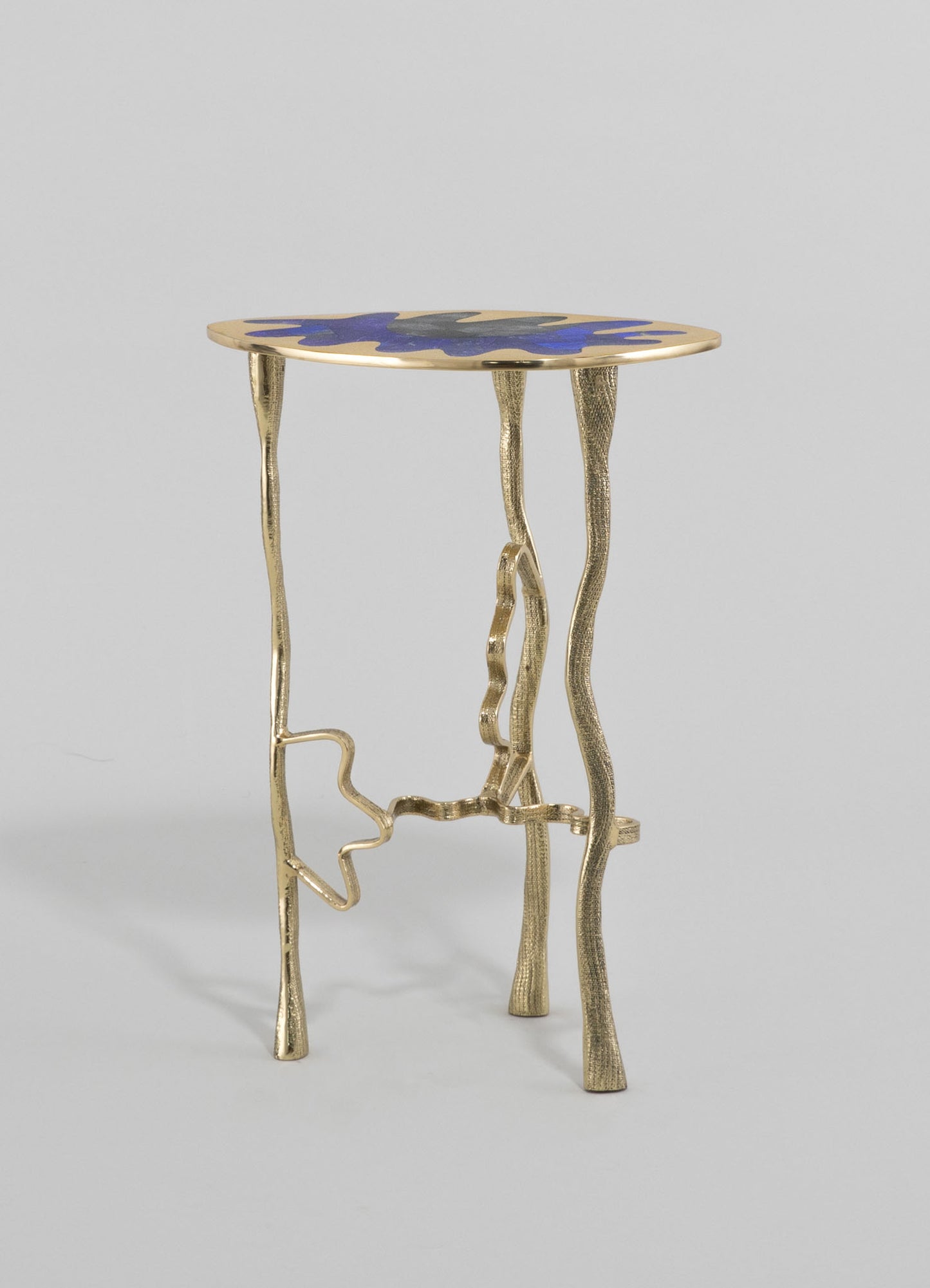 A small side table with a sculptural, irregular gold-colored metal base and a wooden top featuring a blue and black abstract pattern. The design combines contemporary style with artistic craftsmanship.