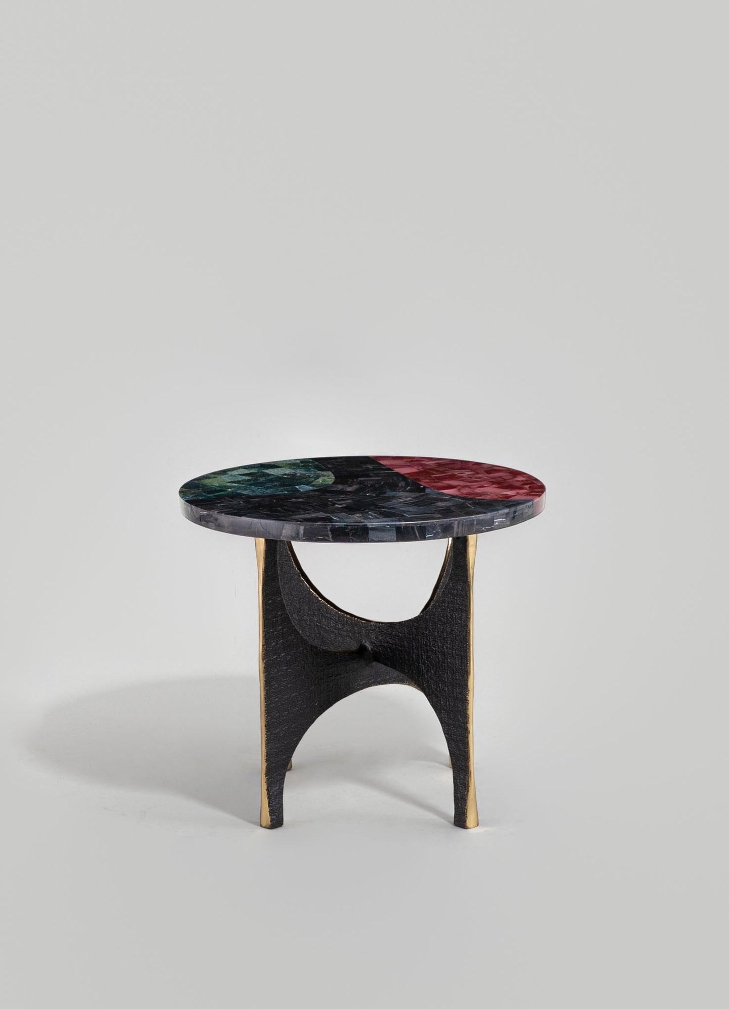 A small side table with a round top made of multicolored marble, featuring green, red, and black tones, and a black wooden base with a curved, arch-shaped support accented by gold trim.