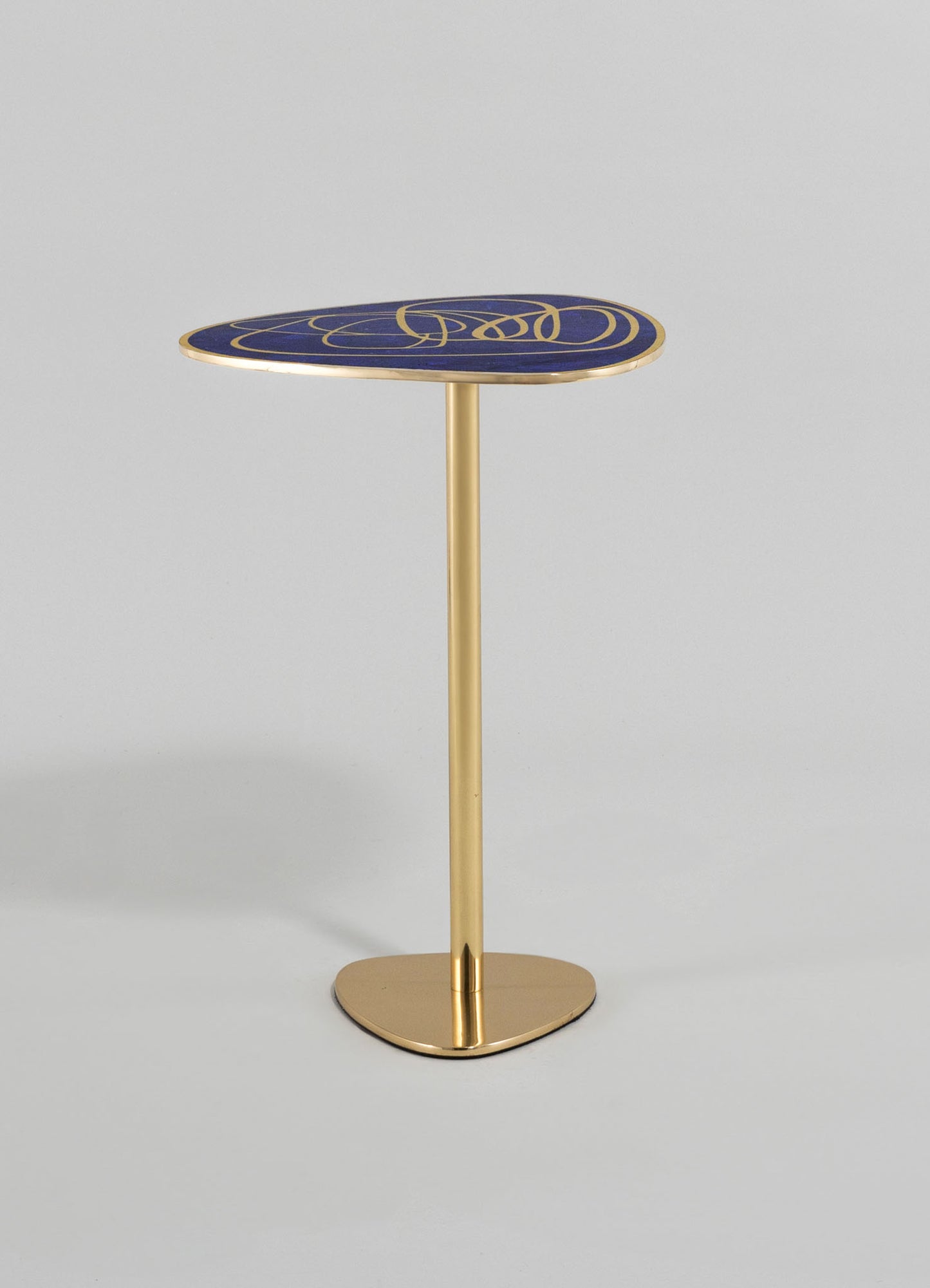 A side table with a gold metallic base and a solid oval top featuring a dark blue finish with gold abstract swirling motifs. The table has a contemporary style with a sleek, minimalist design.