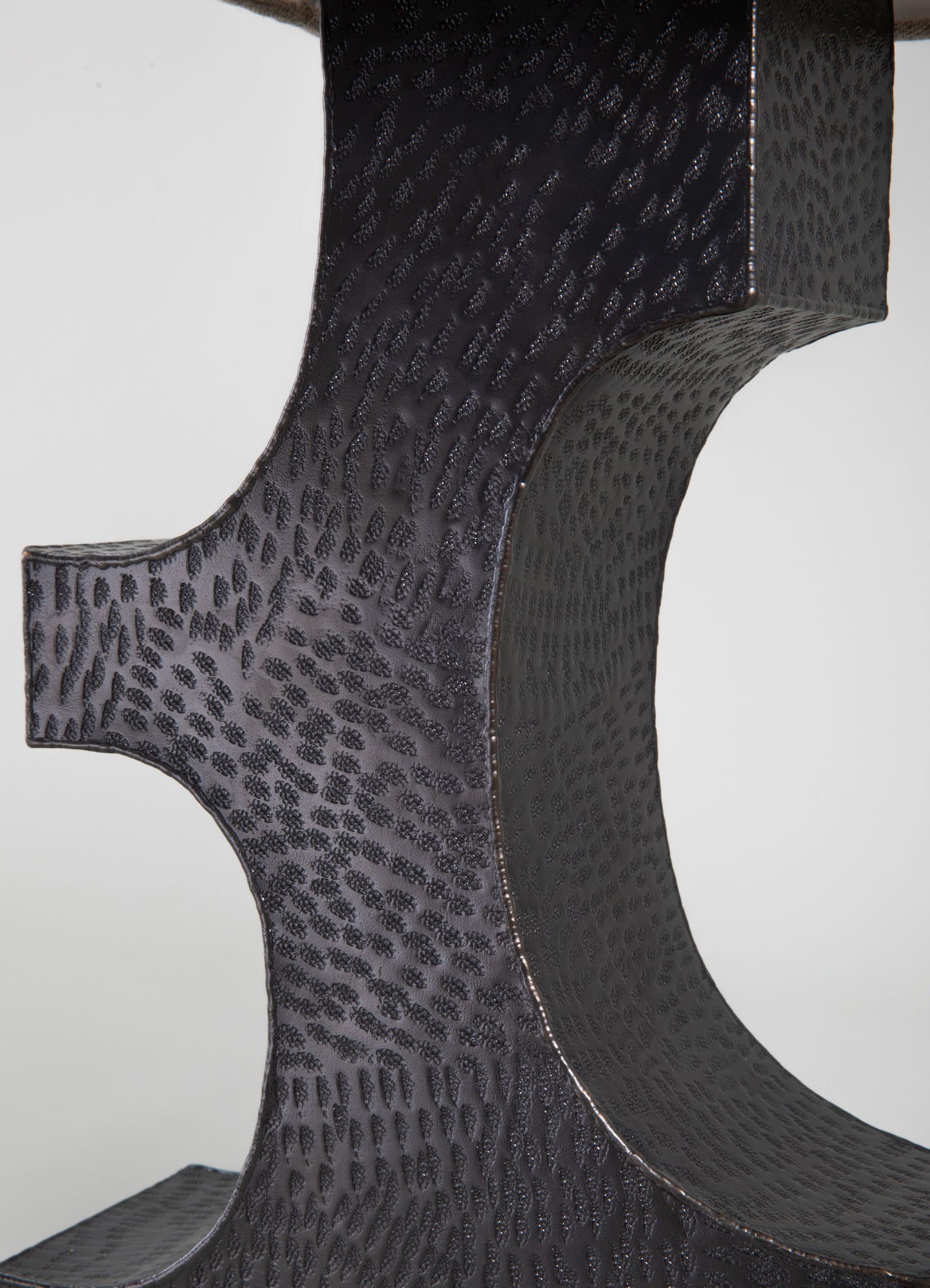 Close-up of a black leather table or decorative piece featuring a textured, pebbled surface with a subtle animal print motif. The material appears leather with a glossy finish, and the design emphasizes the tactile pattern and craftsmanship.