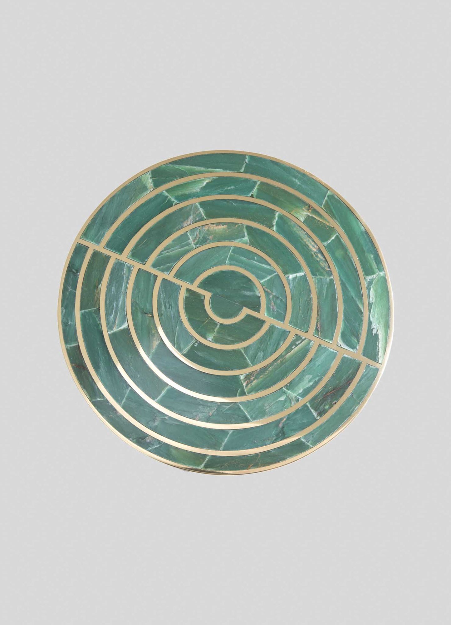 Circular decorative tray with a geometric pattern of concentric circles and a diagonal line, made of green marble with gold-tone metal accents. The tray has a modern, luxurious style with contrasting natural stone and metallic elements.