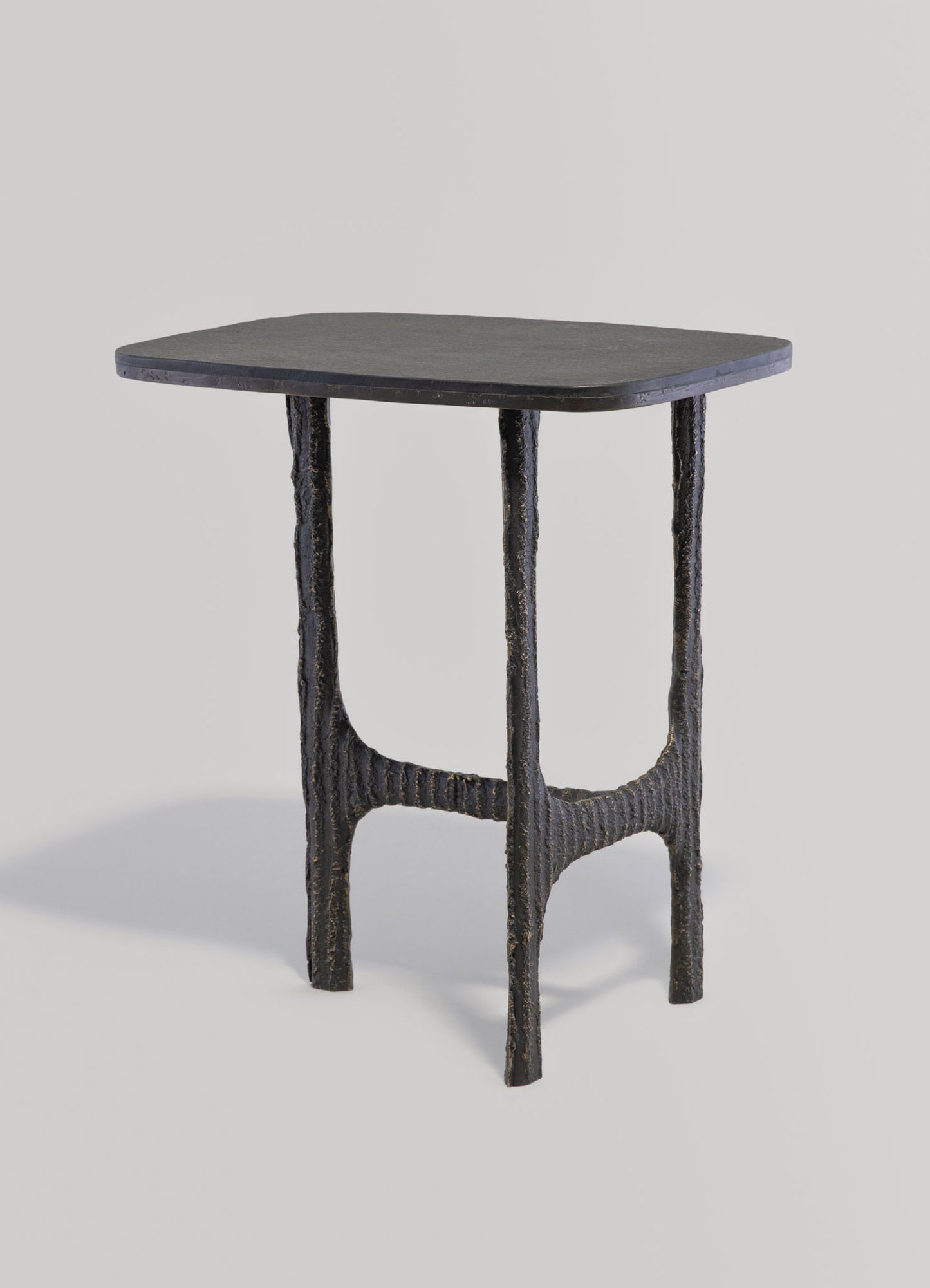 A small side table with a rounded, dark-colored wooden top and textured, black metal legs featuring a rustic, handcrafted finish.