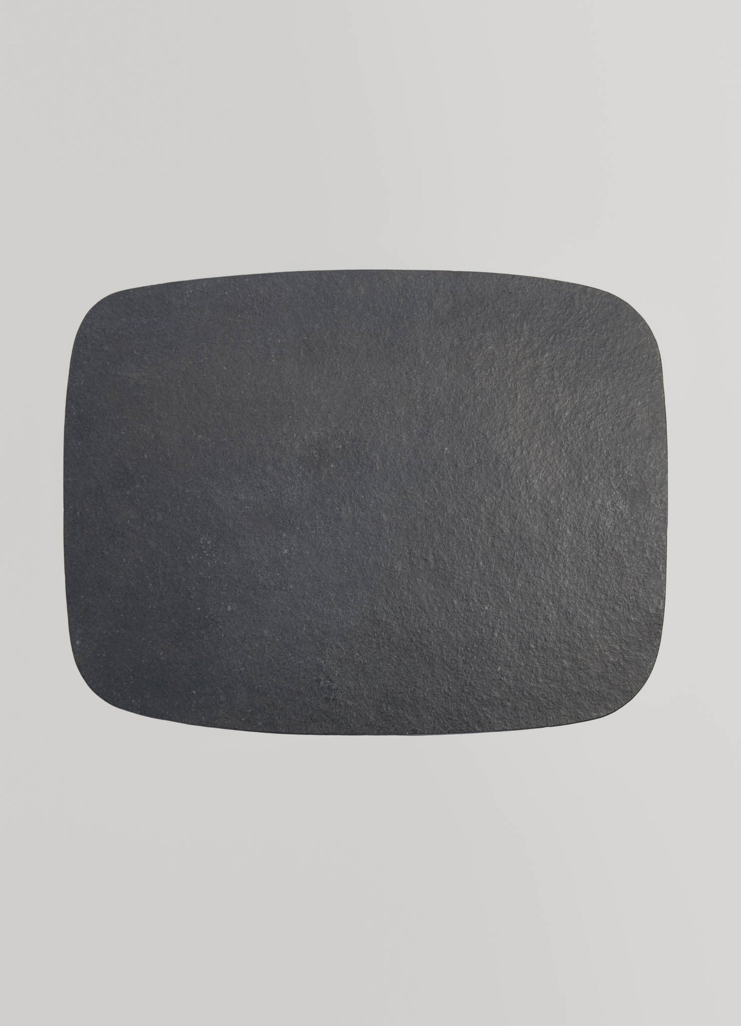 A rectangular black stone coaster with a matte, textured surface, set against a light gray background.