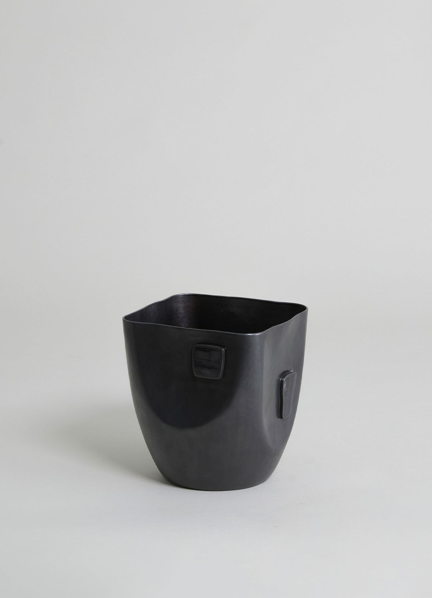 Black ceramic planter with a smooth, matte finish and rectangular side handles, set against a light background.