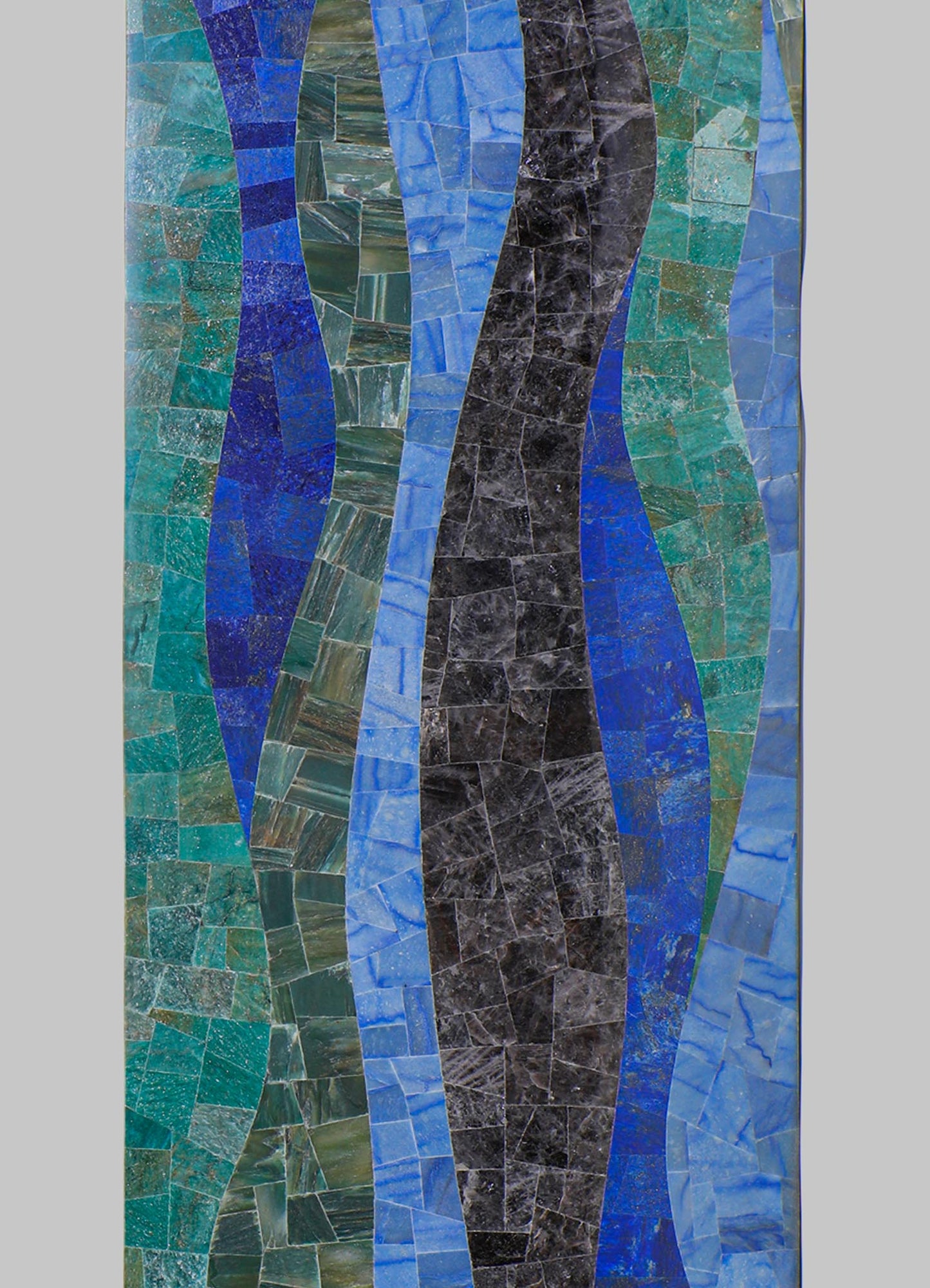 Mosaic artwork featuring irregularly shaped pieces of marble and glass in shades of blue, green, and black, arranged in wavy, organic patterns. The overall style is contemporary with a textured, vibrant surface.