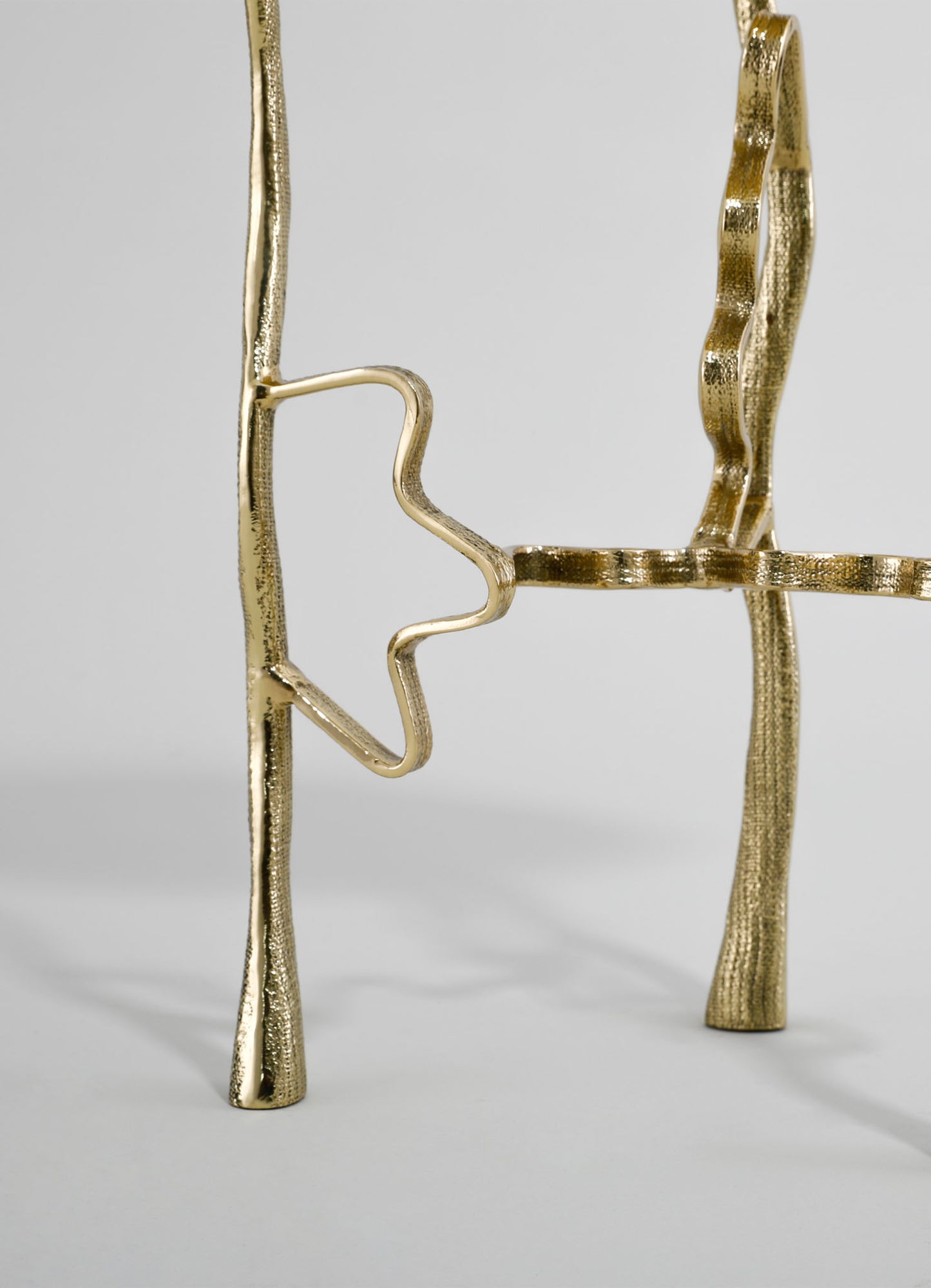 Gold-colored metal chair with a sculptural, wavy design and an abstract star motif on the backrest, featuring a textured surface and contemporary style.