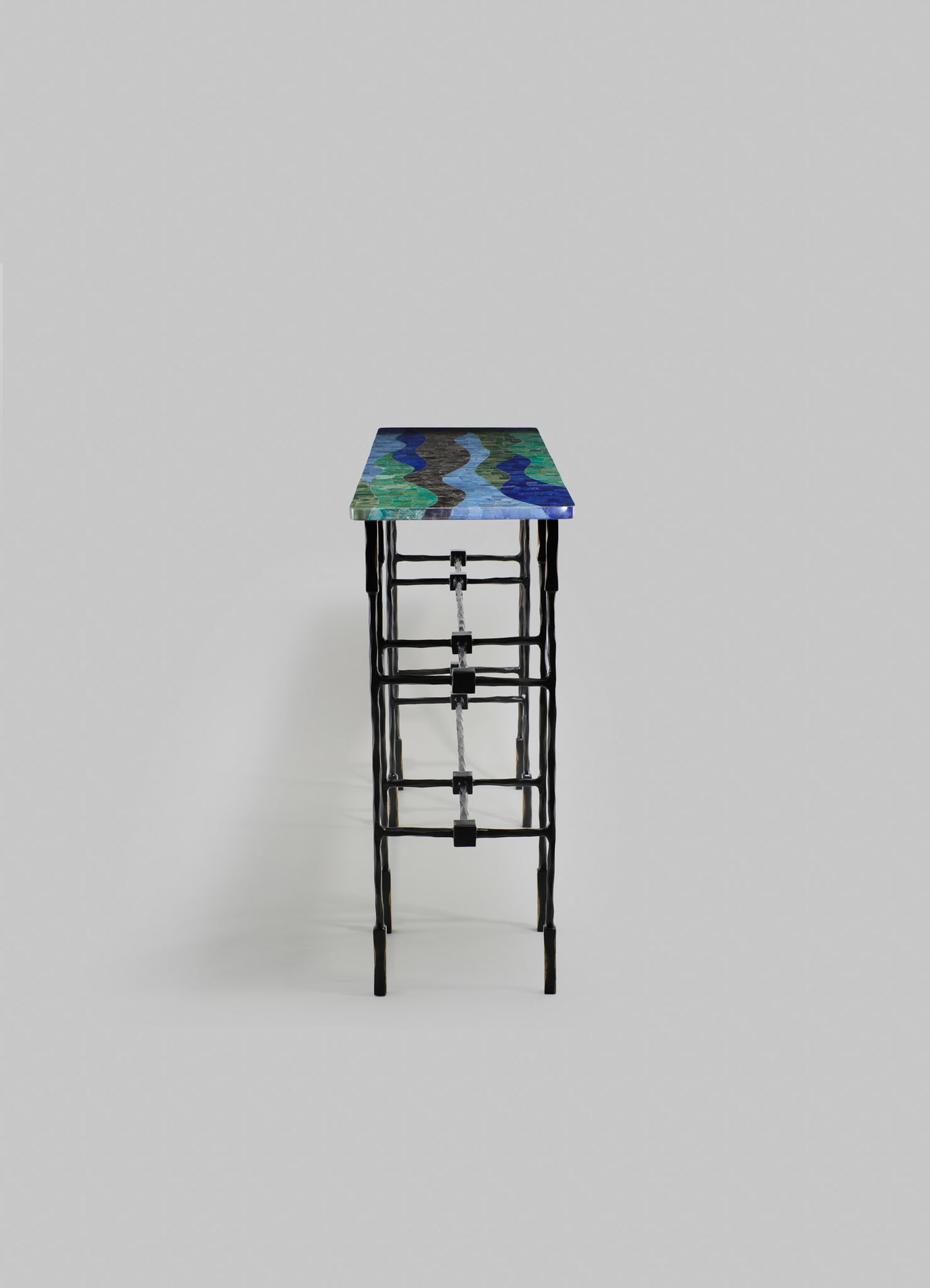 A decorative side table with a rectangular top featuring a colorful, abstract wavy pattern in shades of blue, green, and black, supported by a black metal frame with a geometric, open design.