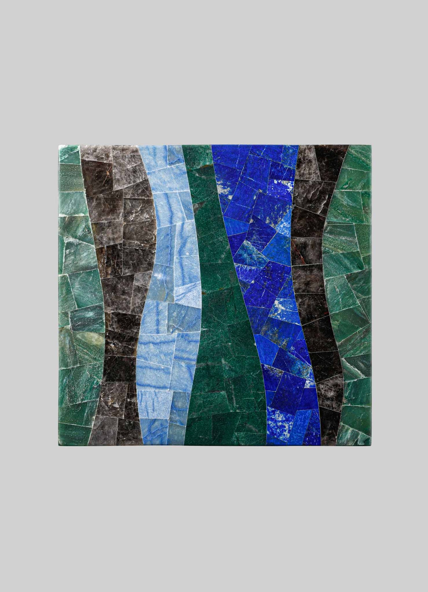 Mosaic artwork composed of irregularly shaped stone and glass pieces in shades of blue, green, black, and gray, arranged in wavy patterns on a rectangular surface. The mosaic has a contemporary style with a textured, vibrant appearance.