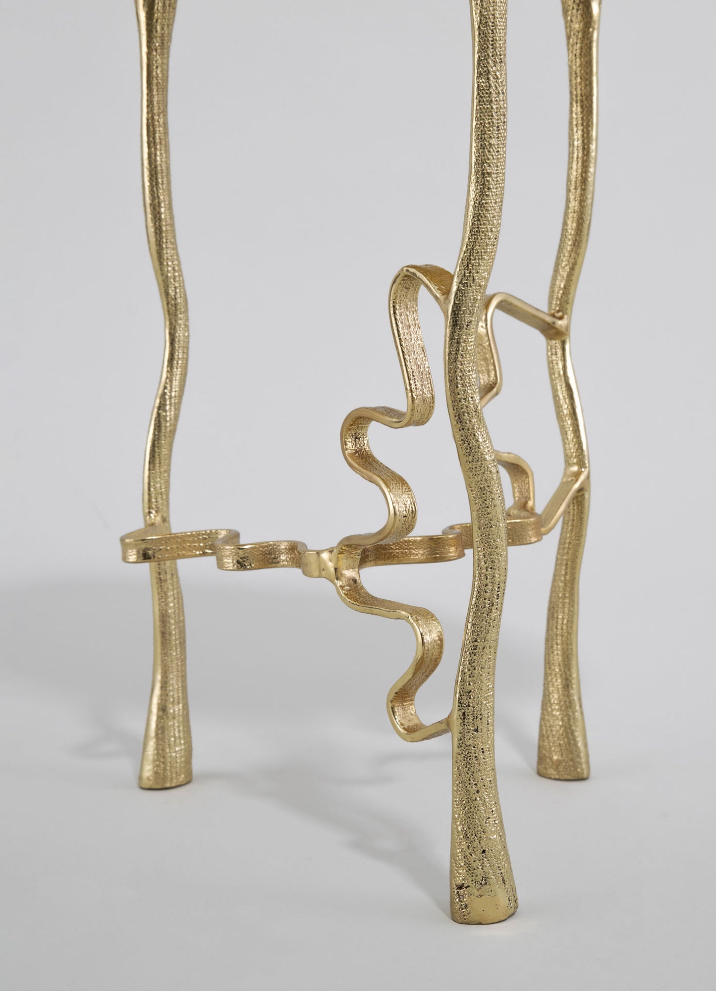 Gold-plated metal sculpture with wavy, irregular lines and a textured finish, featuring abstract, organic shapes on slender, curved legs.