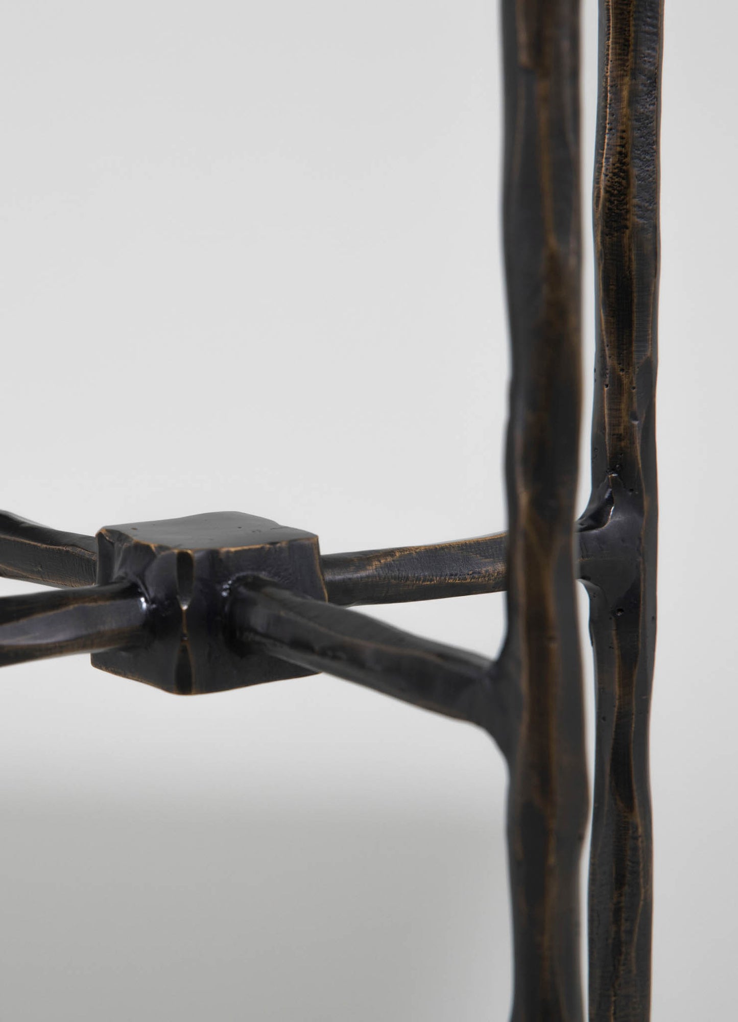 Wooden furniture with a rustic, handcrafted finish featuring dark stained, irregularly shaped legs and a woven seat. The piece exhibits a natural, artisanal style with textured wood surfaces and simple construction.