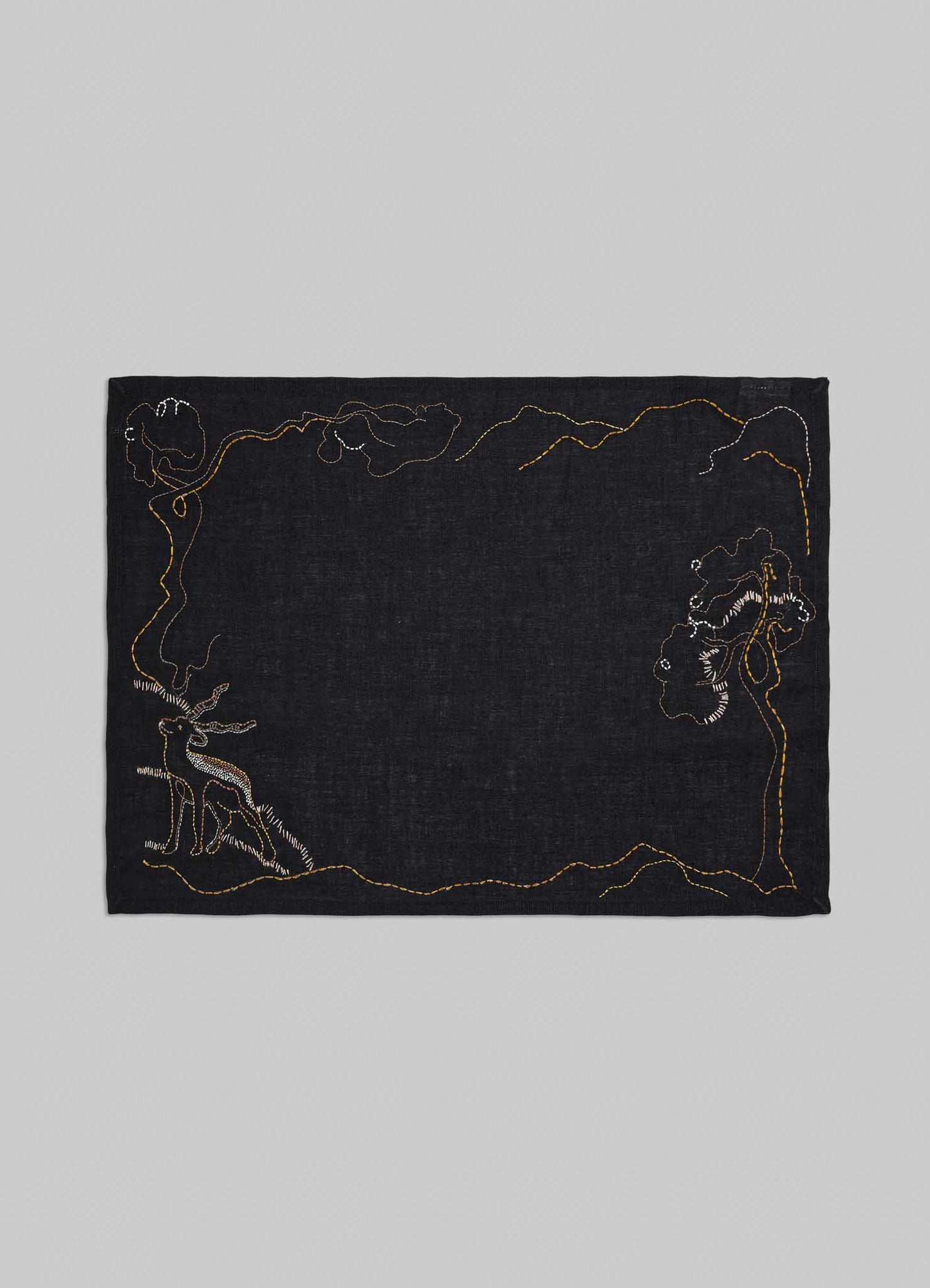 Black fabric with embroidered designs on a gray background placemats viya