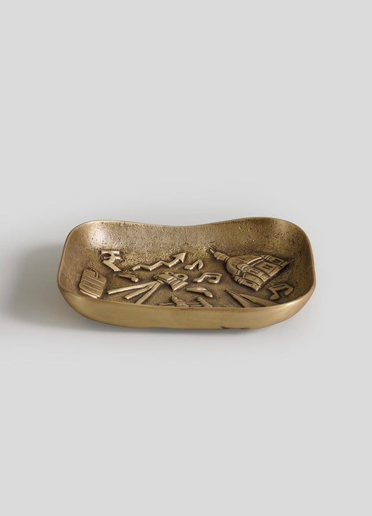 The VIYA Bombay Trinket Bowl is a small, rectangular brass tray featuring raised designs of Washington, D.C. landmarks like the Capitol dome, set against a plain light gray background.
