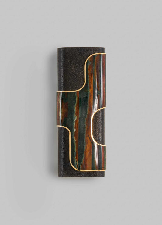 A decorative wall sconce with a cylindrical black textured base, featuring a colorful stone or ceramic insert with green, orange, and brown tones. The design is accentuated by gold-colored metal outlines that create a geometric pattern, giving it a contemporary and artisanal appearance.