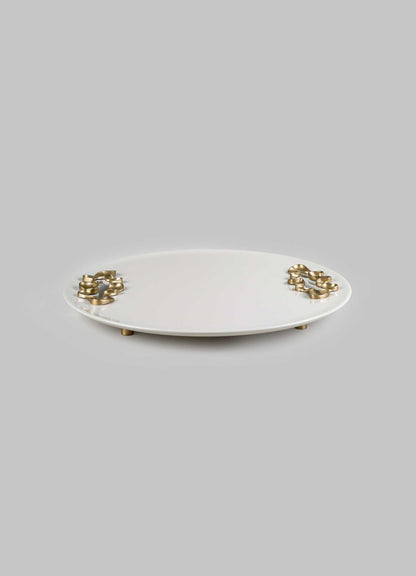 A round ceramic tray with a smooth white finish and metallic gold accents on the edges, supported by small gold-toned feet.