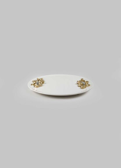 A white ceramic tray with an oval shape, decorated with gold-tone metallic accents that resemble intertwined loops on each end.